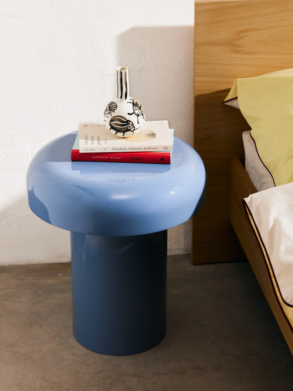 noo.ma Miko Side Table, a sculptural modern minimalist side table with a glossy lacquered finish, featuring a lighter periwinkle blue rounded top and a darker slate blue cylindrical base.