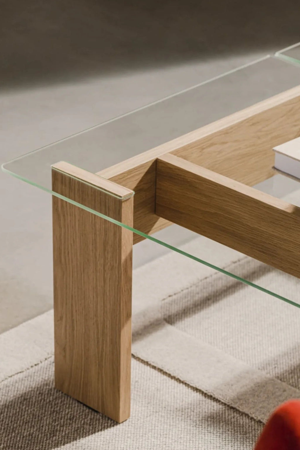 noo.ma Naiko Coffee Table, a modern minimalist coffee table crafted from natural solid oak with a clear tempered glass top, featuring a clean-lined rectangular design and a geometric wooden base. This Scandinavian-inspired piece offers a light, airy aesthetic, ideal for contemporary living rooms and Japandi interiors.