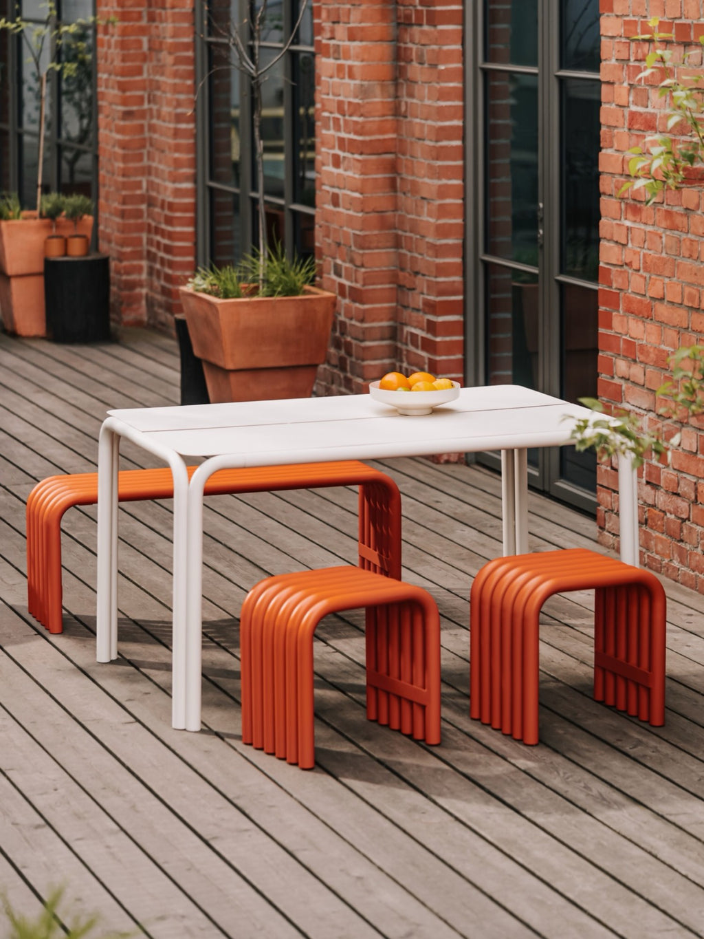 noo.ma Nokk Bench, a striking modern outdoor bench in a vibrant terracotta orange hue, constructed from durable powder-coated tubular steel.