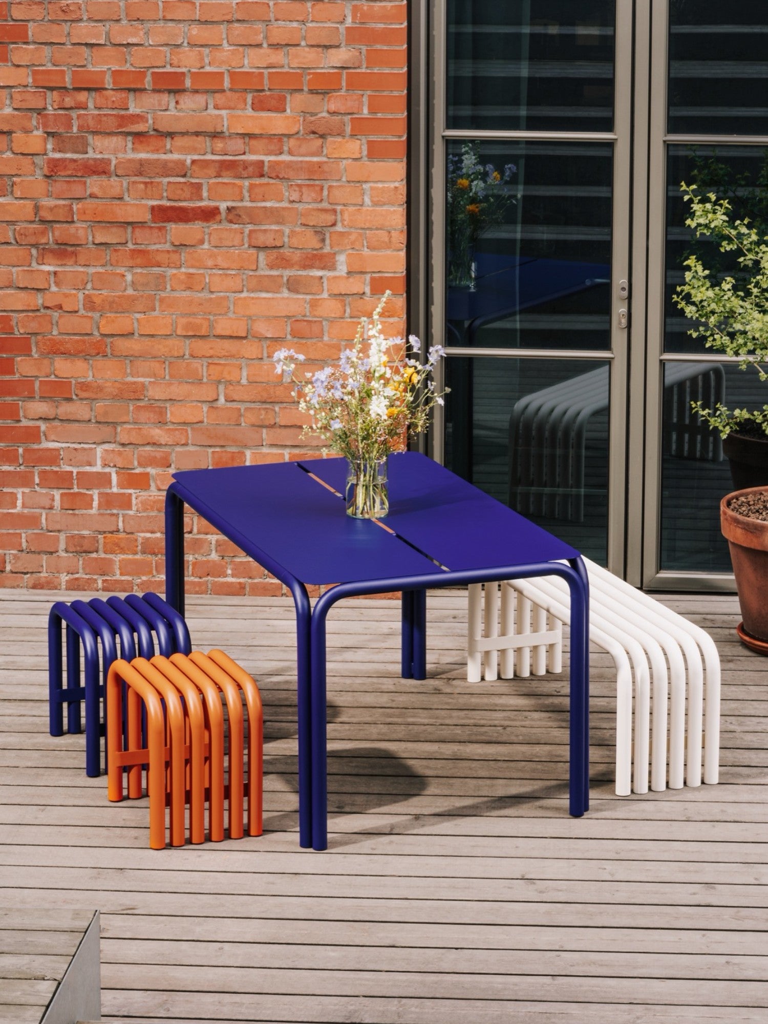 noo.ma Nokk Bench, a modern minimalist outdoor bench crafted from durable cream powder-coated steel, featuring a distinctive slatted design with curved tubular elements forming the seat and legs.