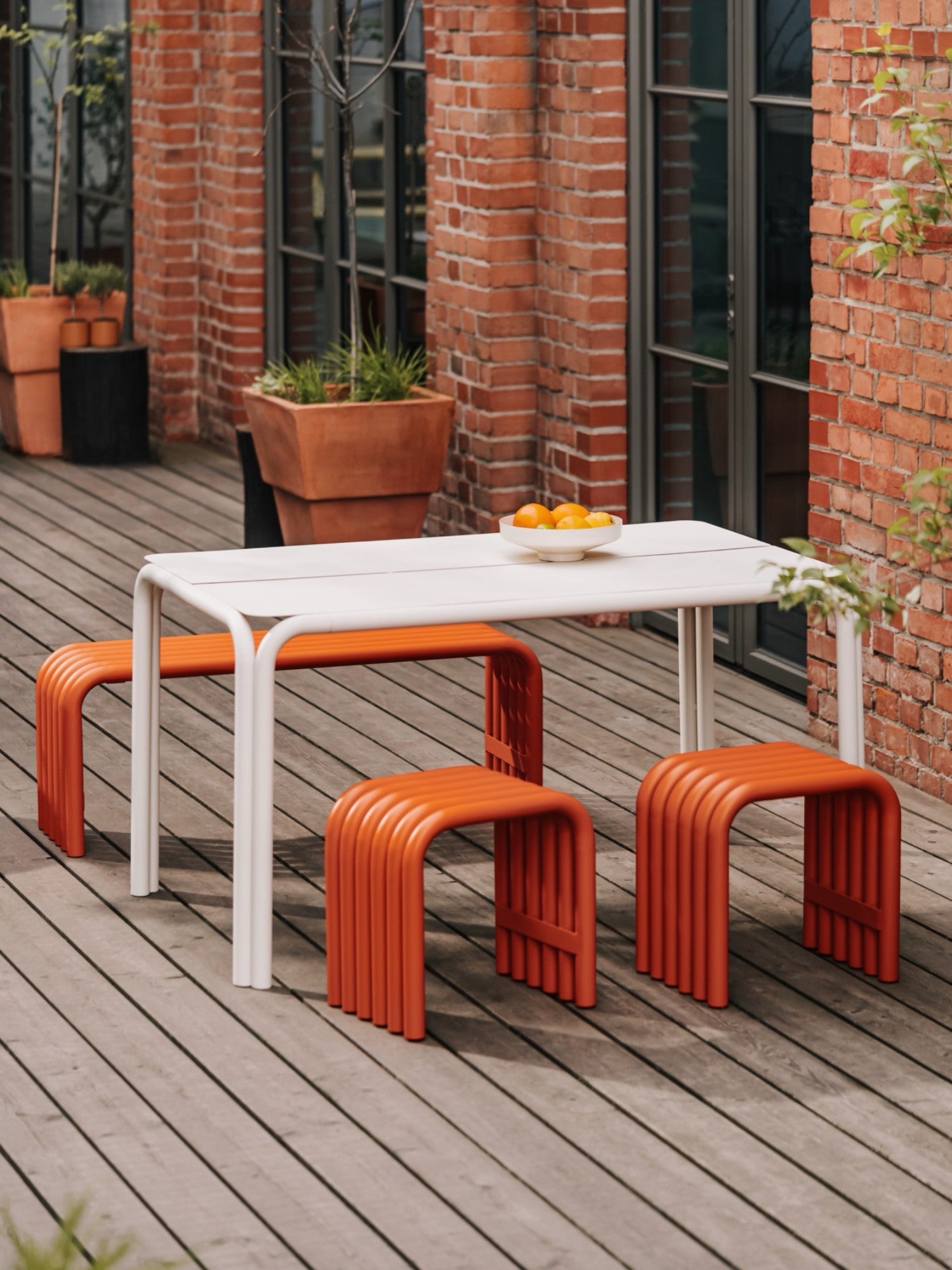 noo.ma Nokk Stool, a vibrant orange powder-coated steel stool featuring a distinctive U-shaped design crafted from multiple curved metal tubes, creating a modern ribbed texture and playful silhouette. This durable contemporary outdoor stool is perfect for adding a pop of color to patios, balconies, or as a minimalist accent bench in modern living spaces.