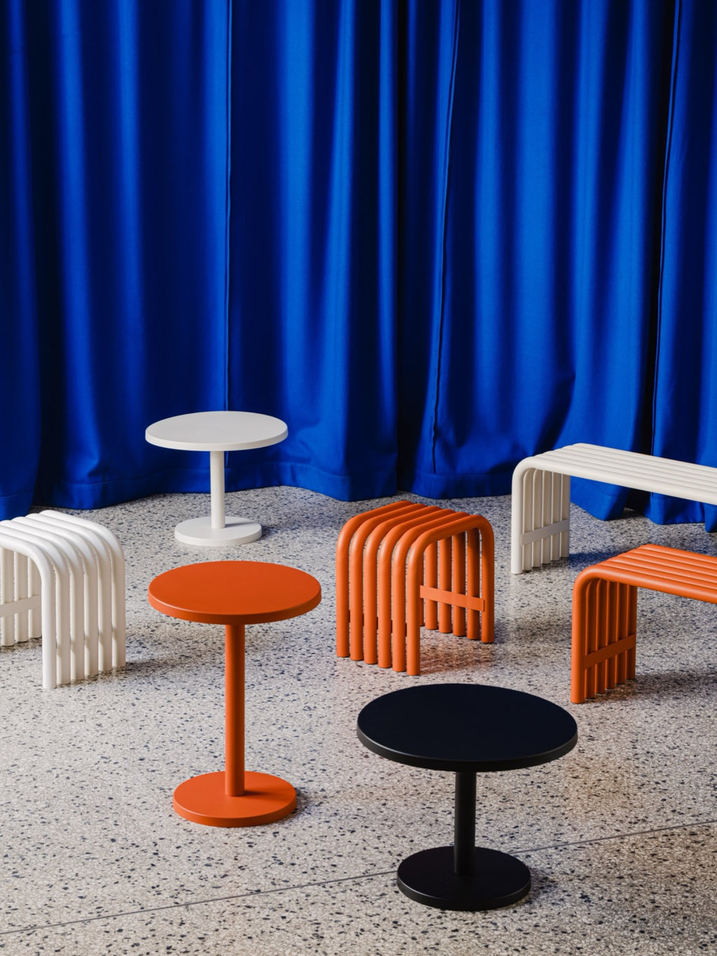 noo.ma Nokk Stool, a contemporary minimalist stool crafted from durable powder-coated steel, available in vibrant orange or crisp white, featuring a distinctive ribbed design with curved bent metal tubing.