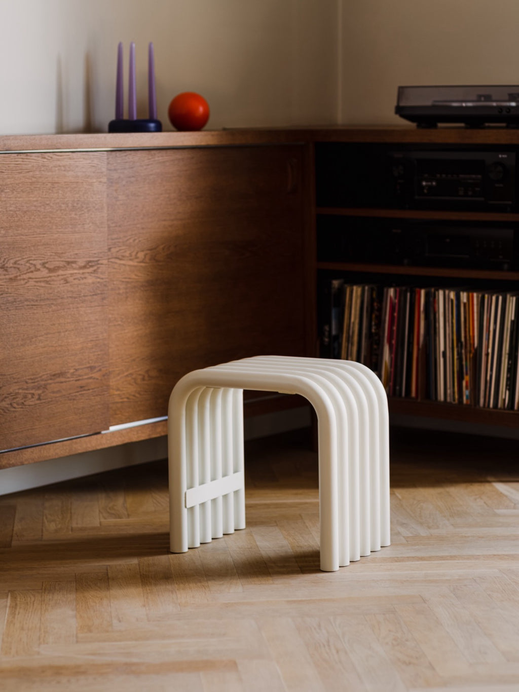 noo.ma Nokk Stool, a modern minimalist accent stool featuring a distinctive off-white fluted design with multiple curved, rounded elements forming a seamless U-shaped profile and a smooth matte finish. This contemporary organic modern stool is perfect as a decorative side table or extra seating for living rooms, bedrooms, or entryways.