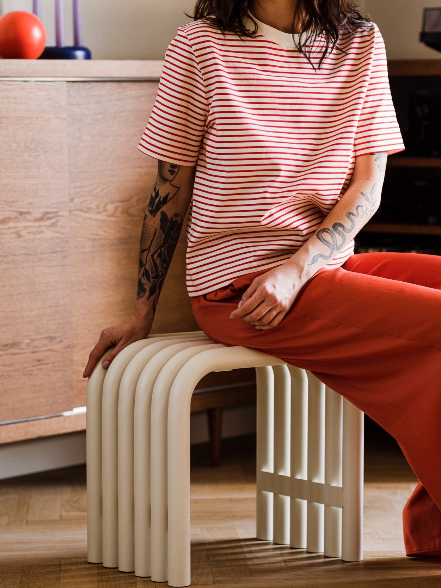noo.ma Nokk Stool, a sculptural modern minimalist accent stool in a warm matte beige finish, featuring a unique ribbed design with continuous, smoothly curved vertical elements that form its U-shaped profile. Crafted with a durable lacquer, this contemporary stool offers a striking silhouette. Perfect as a versatile side table or extra seating for organic modern and Scandinavian-inspired living rooms or entryways.
