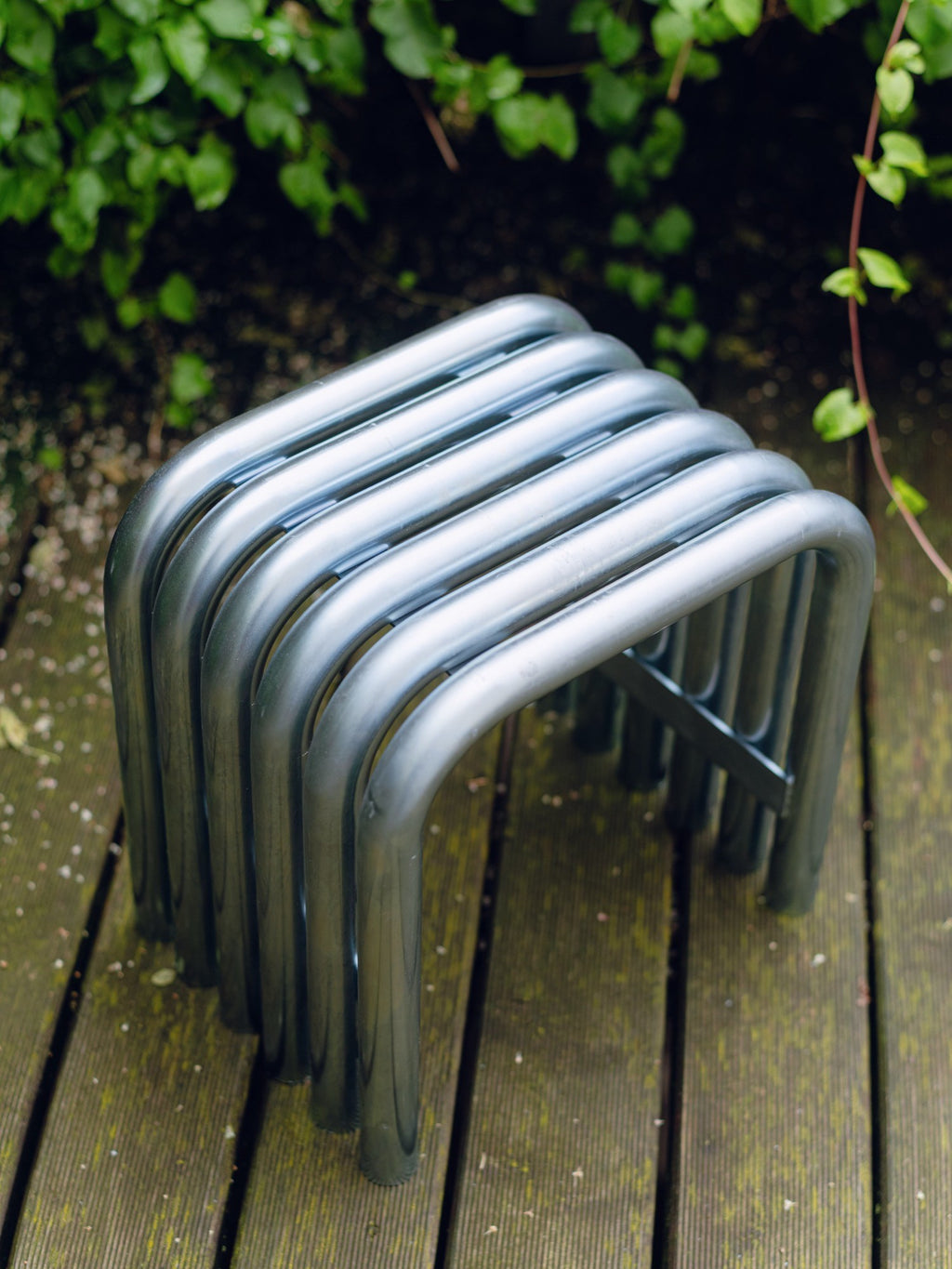 noo.ma Nokk Stool, a modern minimalist stool crafted from durable anthracite dark grey powder-coated tubular steel, featuring a distinctive ribbed design formed by multiple U-shaped metal elements. This versatile and robust metal bench is perfect for contemporary entryways, industrial living rooms, or stylish outdoor patio seating.