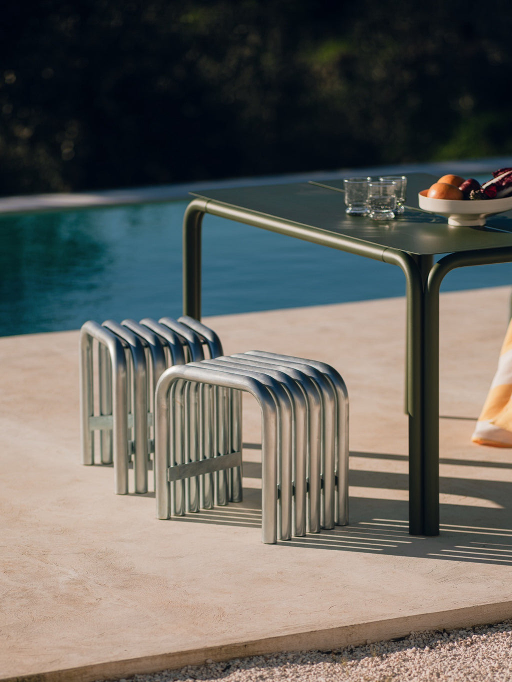 noo.ma Nokk Stool, an industrial chic outdoor stool crafted from durable silver metal tubing, featuring a unique ribbed design formed by multiple U-shaped elements. This modern minimalist metal stool is perfect for poolside seating, garden patios, or contemporary outdoor spaces.