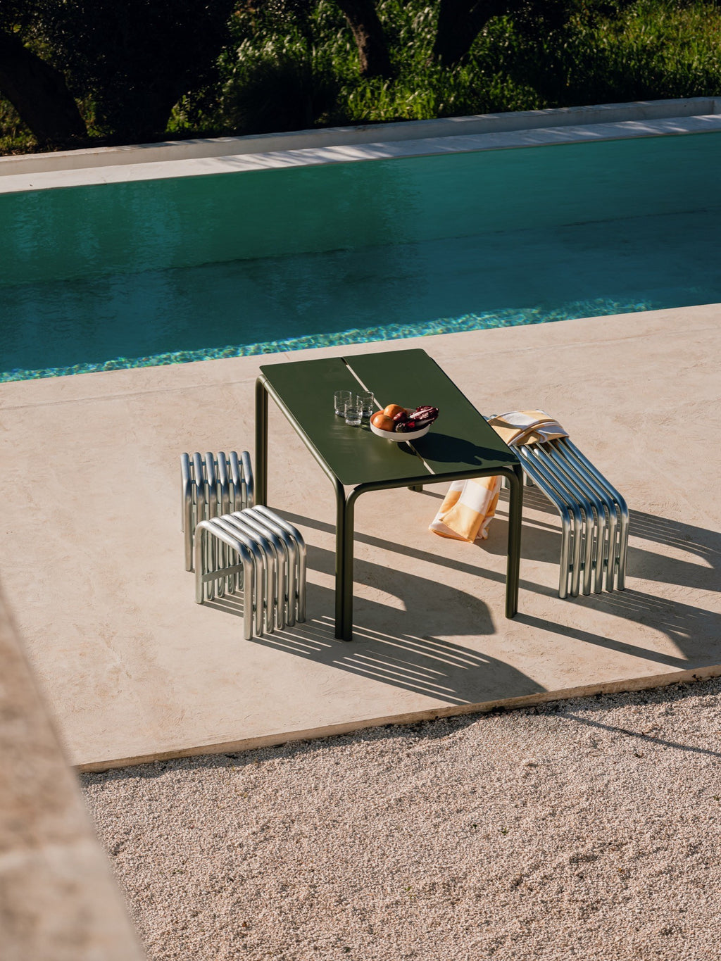 noo.ma Nokk Stool, a modern minimalist outdoor stool crafted from polished silver-tone metal tubes, featuring a distinctive U-shaped design with parallel ribbed seating and legs. This contemporary industrial chic stool is perfect for stylish poolside seating, a modern patio, or a garden accent.