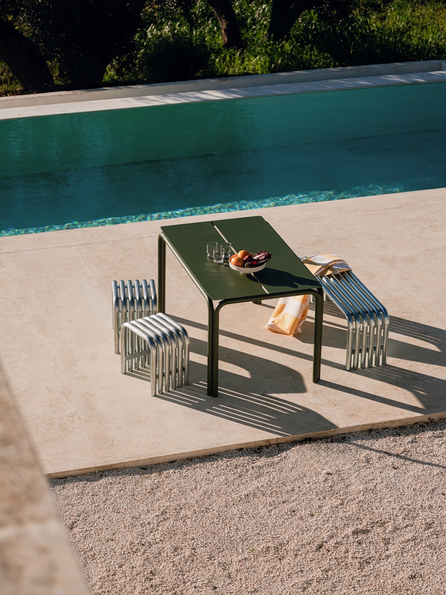 noo.ma Nokk Stool, a modern minimalist outdoor stool crafted from polished silver-tone metal tubes, featuring a distinctive U-shaped design with parallel ribbed seating and legs. This contemporary industrial chic stool is perfect for stylish poolside seating, a modern patio, or a garden accent.