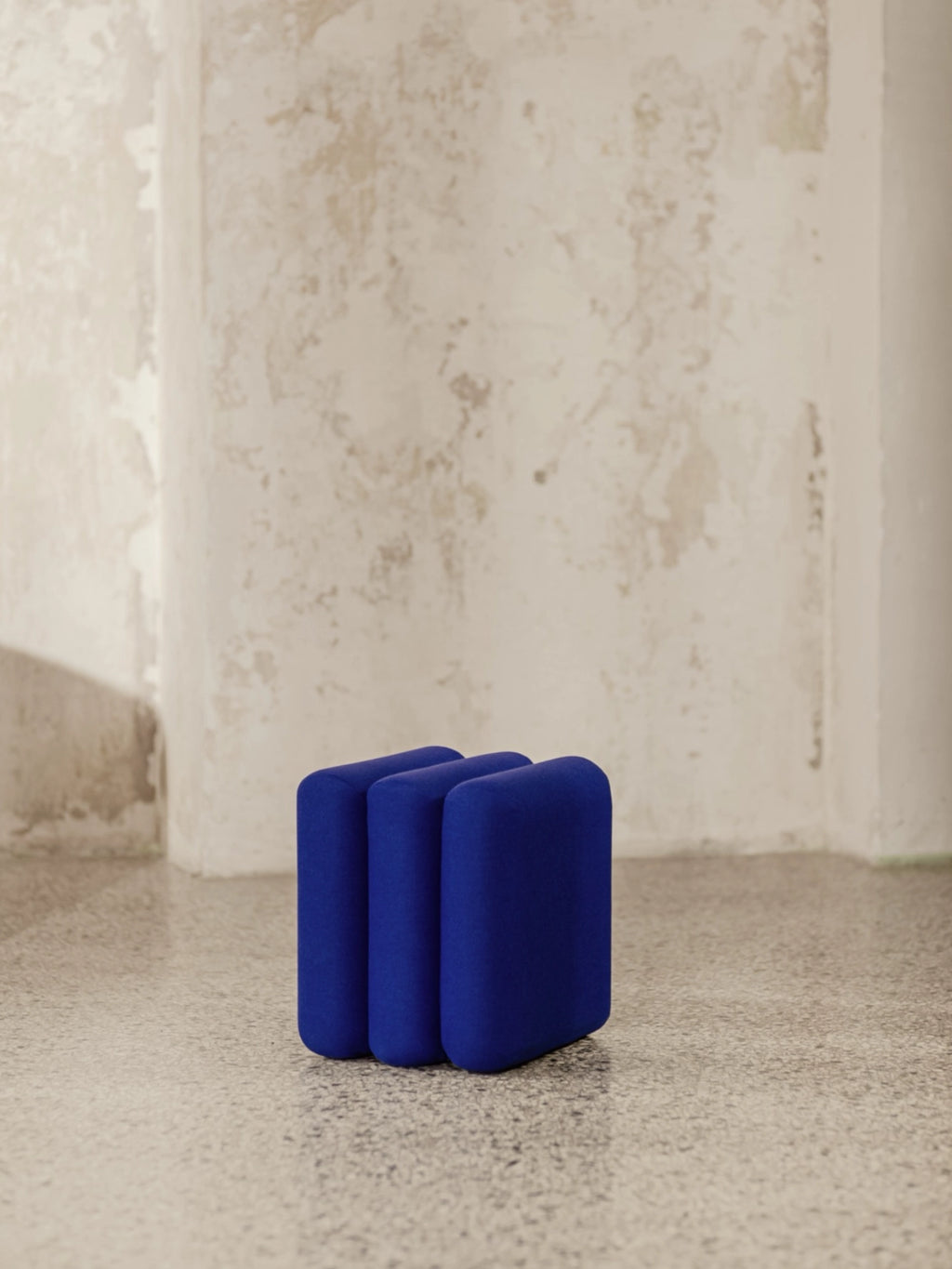 noo.ma Radd Pouf, a vibrant royal blue upholstered pouf featuring a distinct sculptural design with three plush, rounded columnar forms joined together.