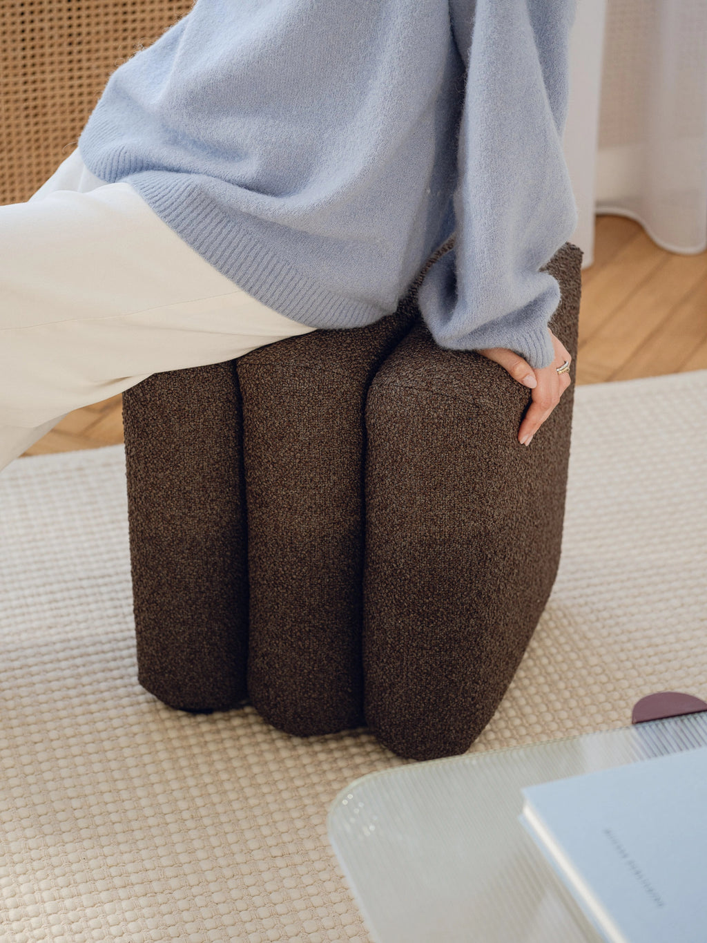 noo.ma Radd Pouf, a sculptural dark brown pouf featuring a distinctive organic, fluted design with three rounded segments, upholstered in a rich, textured bouclé fabric. This contemporary accent stool offers plush seating and a unique visual anchor, perfect for minimalist living rooms, organic modern bedrooms, or as a stylish entryway ottoman.