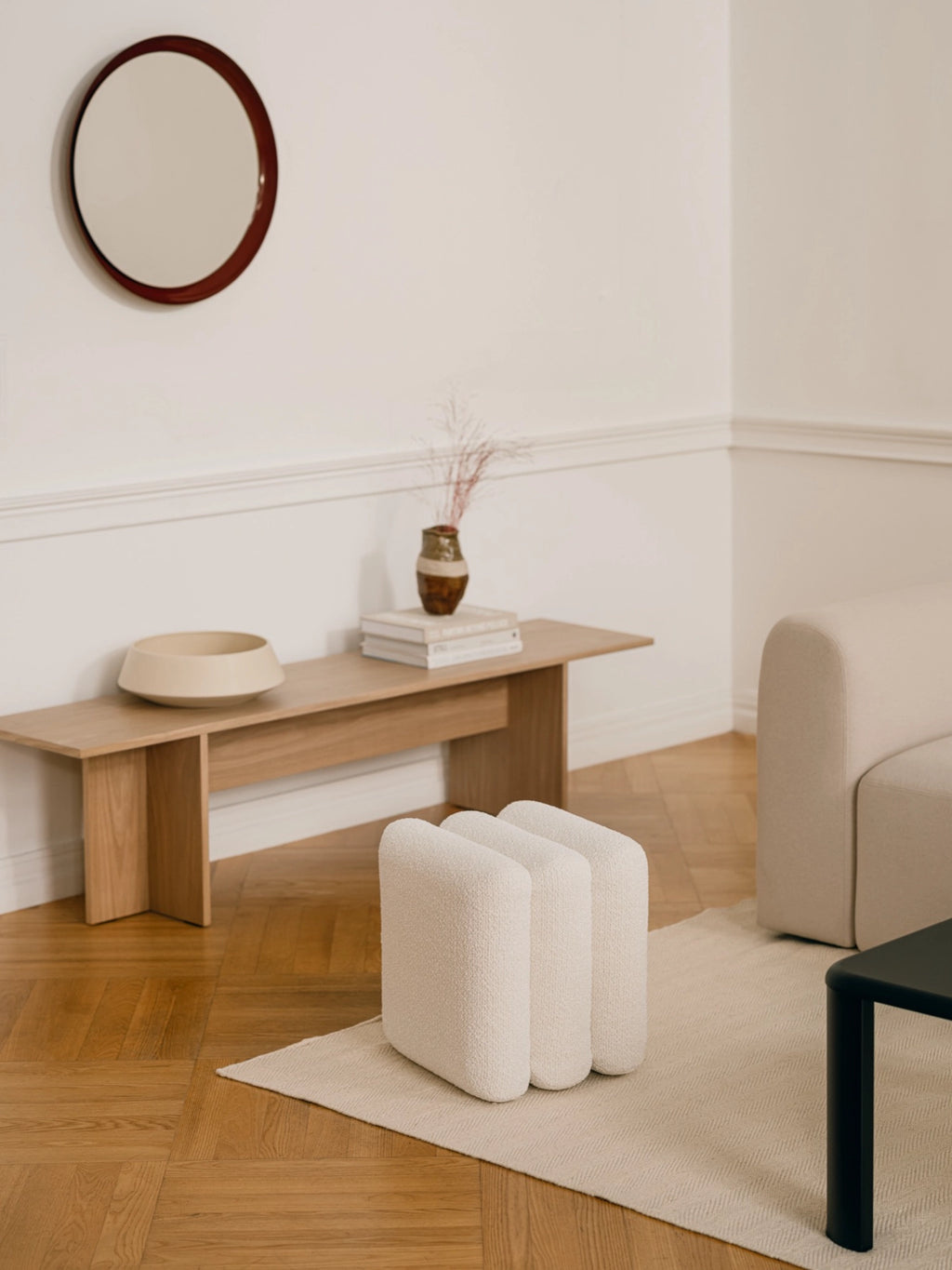 noo.ma Radd Pouf, a minimalist and organic modern pouf featuring three distinct, rounded modules upholstered in a soft, textured cream bouclé fabric. This unique accent seating piece offers a cozy yet refined aesthetic with its sculptural shape and neutral color. Perfect as an adaptable bouclé ottoman for living room, bedroom, or entryway styling in contemporary or Scandinavian interiors.