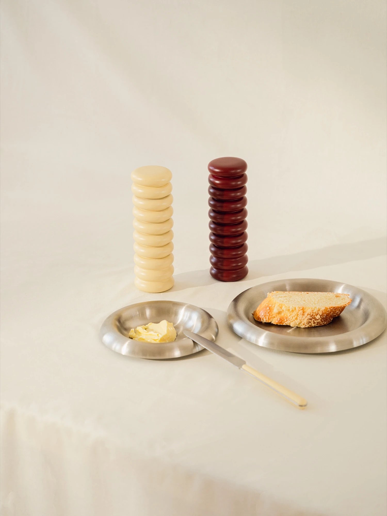 Two steel plates with stacked items on a beige background