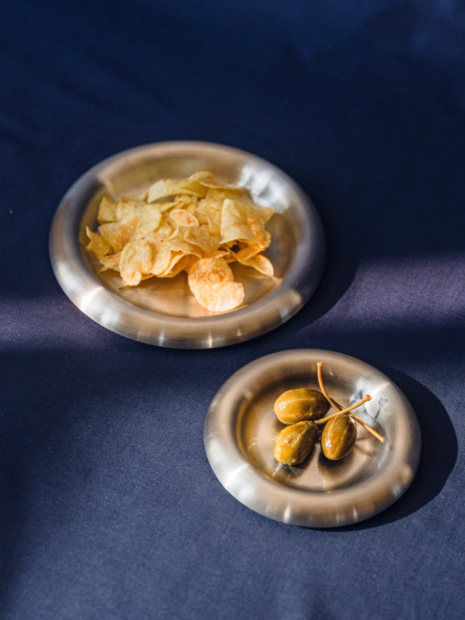 Two small steel plates with snacks on a dark blue background