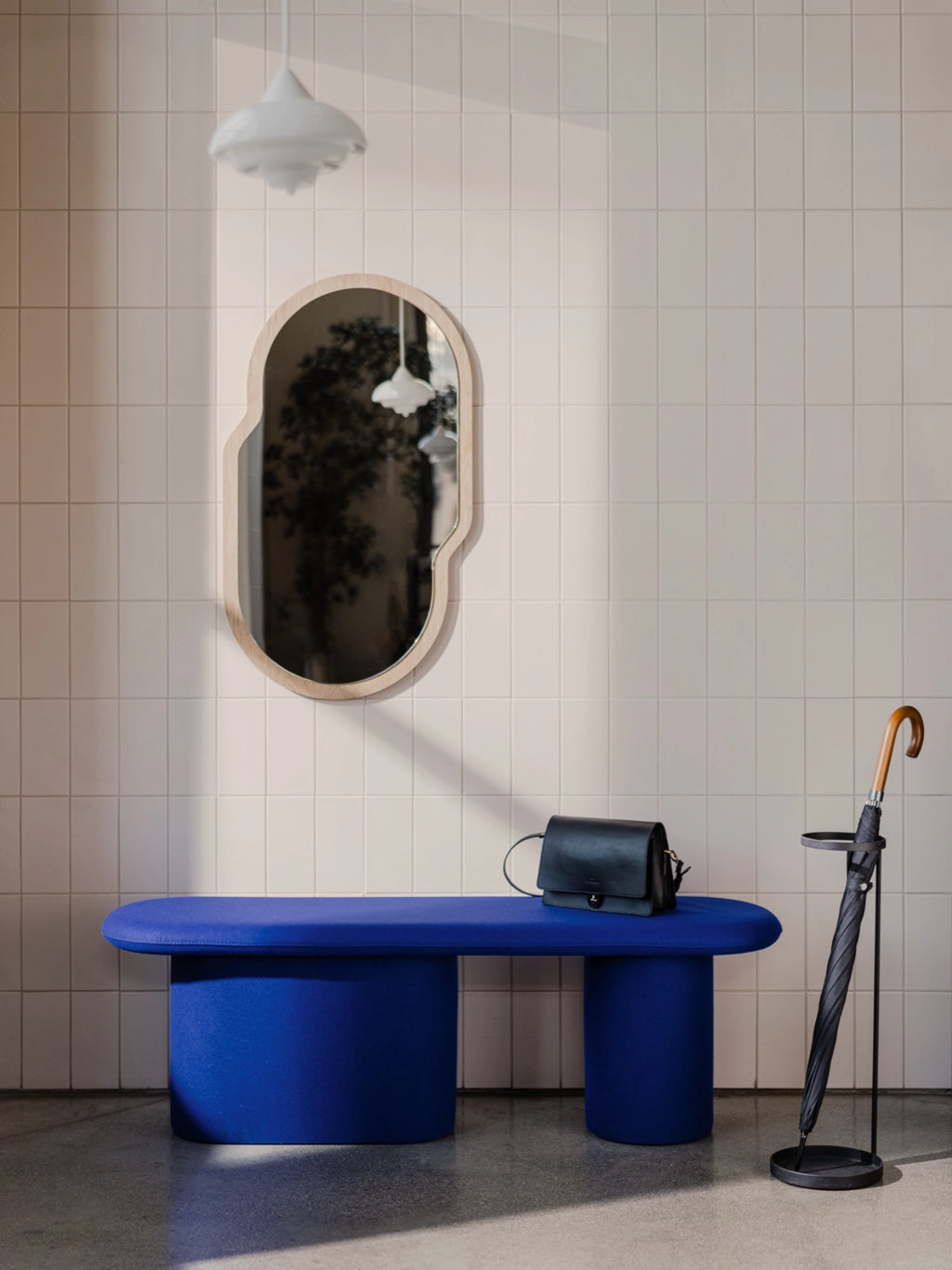noo.ma Rull Bench, a vibrant electric blue fabric upholstered bench featuring an elongated, rounded rectangular top and two sturdy cylindrical bases, embodying a modern minimalist and organic contemporary design.