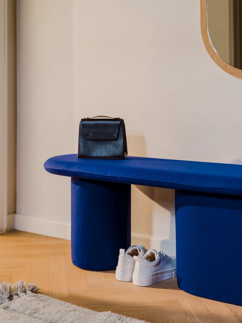 noo.ma Rull Bench, a vibrant royal blue upholstered bench featuring a modern minimalist design with a soft, rounded pill-shaped top and two sculptural cylindrical legs, fully covered in a smooth, felt-like fabric. This contemporary accent bench is perfect for adding a pop of color to an entryway, living room, or bedroom in organic modern and Scandinavian-inspired interiors.