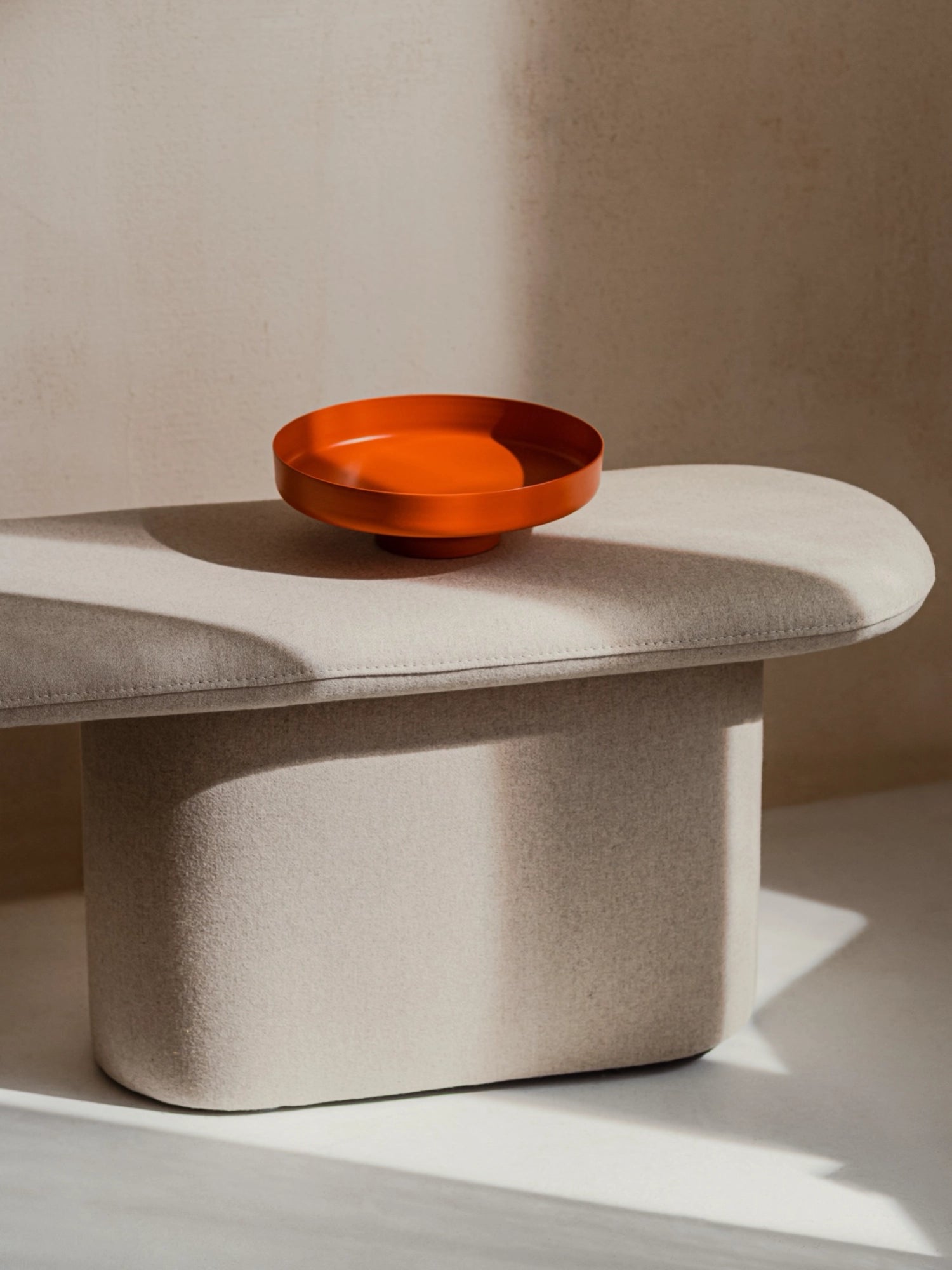 noo.ma Rull Bench, a modern minimalist upholstered bench featuring a soft beige felt fabric with a rounded, organic pill-shaped top and a sturdy, curved base. This contemporary greige bench offers comfortable seating or can serve as a stylish side table in living rooms, bedrooms, or entryways, perfect for organic modern interiors.