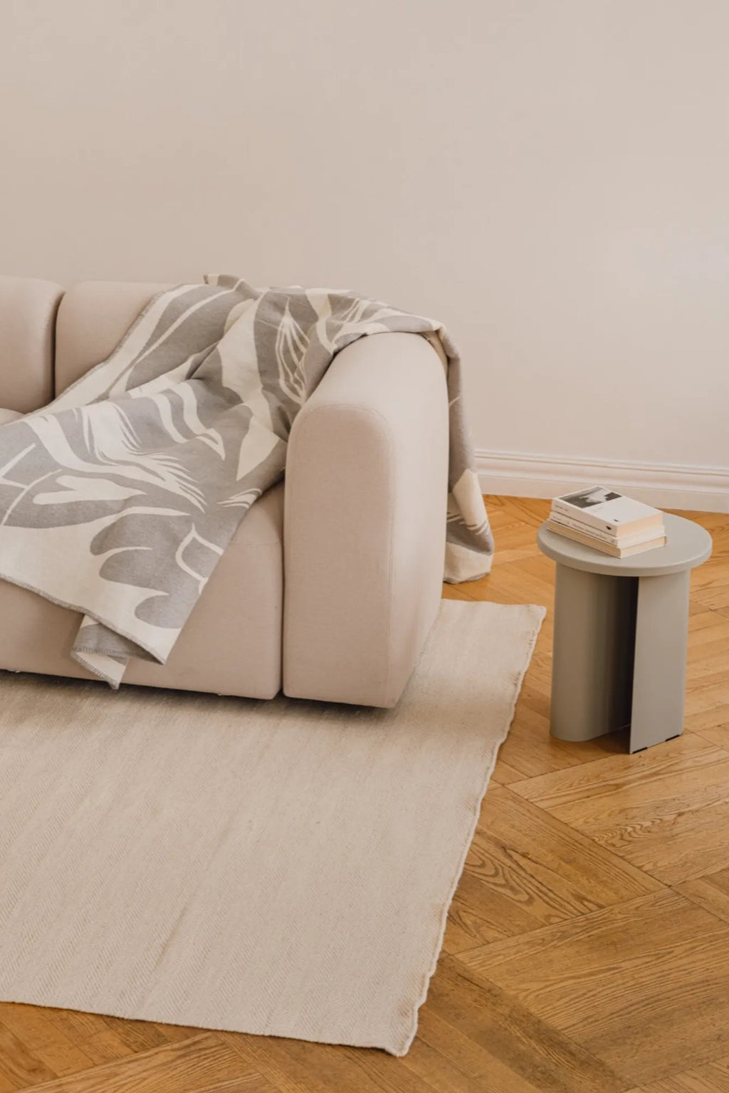 noo.ma Sato Side Table, a modern minimalist side table featuring a round top and a sculptural cylindrical base with a distinctive curved cut-out, all in a muted sage green matte finish.