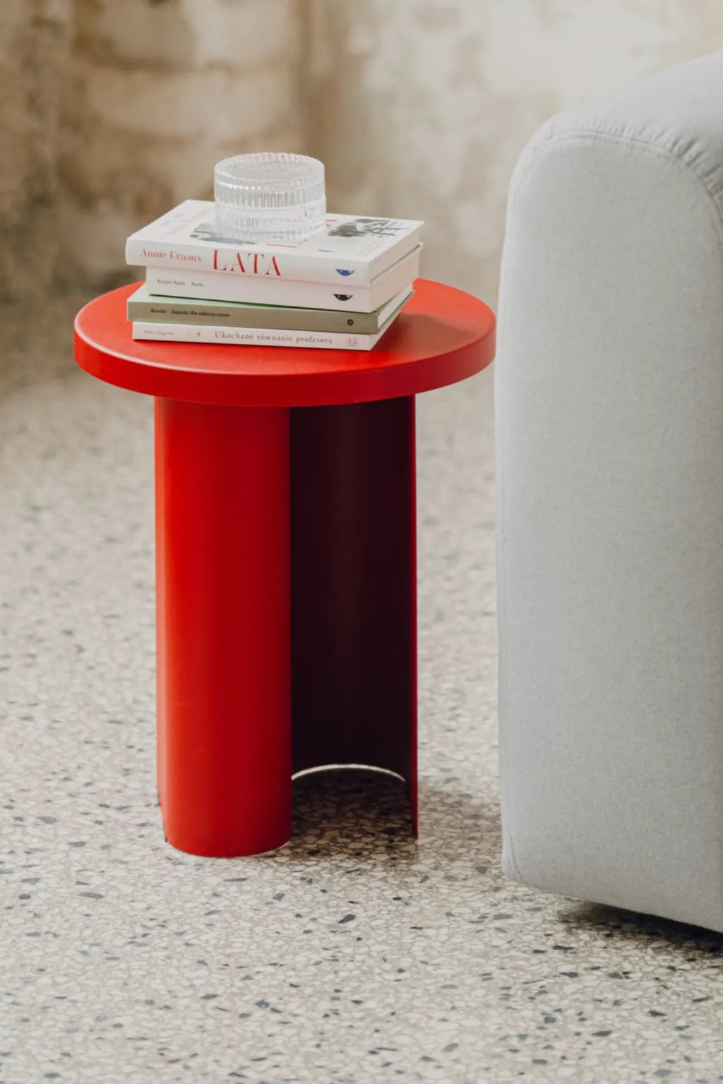 noo.ma Sato Side Table, a vibrant red modern minimalist side table crafted from smooth powder-coated metal, featuring a sleek round tabletop and a sculptural cylindrical base with a unique curved cut-out. This contemporary accent table is perfect for adding a bold pop of color and geometric style to modern living rooms, bedrooms, or small apartment interiors.