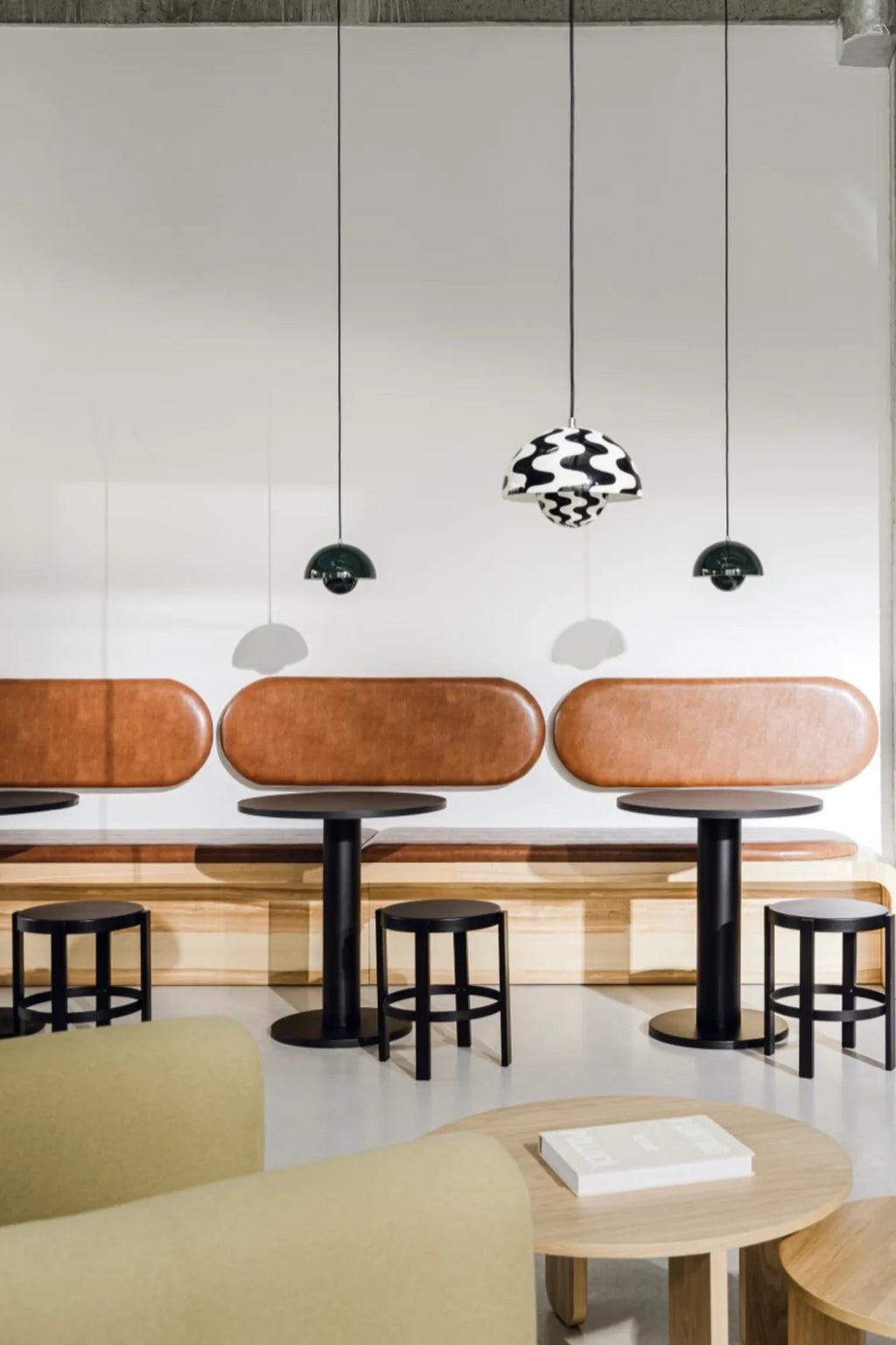 noo.ma Sool Café Table, a sleek round matte black metal café table featuring a sturdy cylindrical pedestal base and a minimalist design. This modern bistro table offers a contemporary industrial chic aesthetic, ideal for restaurant dining areas, coffee shops, or small kitchen nooks.