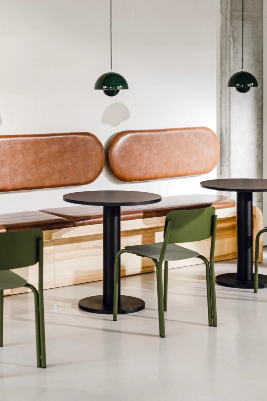 noo.ma Sool Café Table, a sleek modern minimalist dining table featuring a round matte black tabletop and a sturdy cylindrical matte black metal pedestal base. This contemporary black metal café table is perfect for industrial chic bistros, small apartment dining areas, or modern commercial restaurant settings.