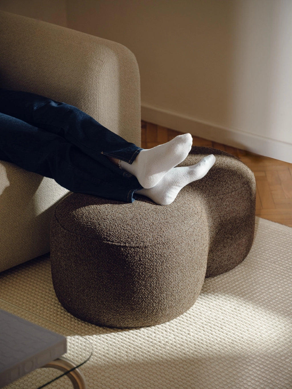 noo.ma Umbo Pouf, a deep taupe contemporary pouf featuring a unique double-lobed organic silhouette, upholstered in a rich, textured bouclé-like fabric.