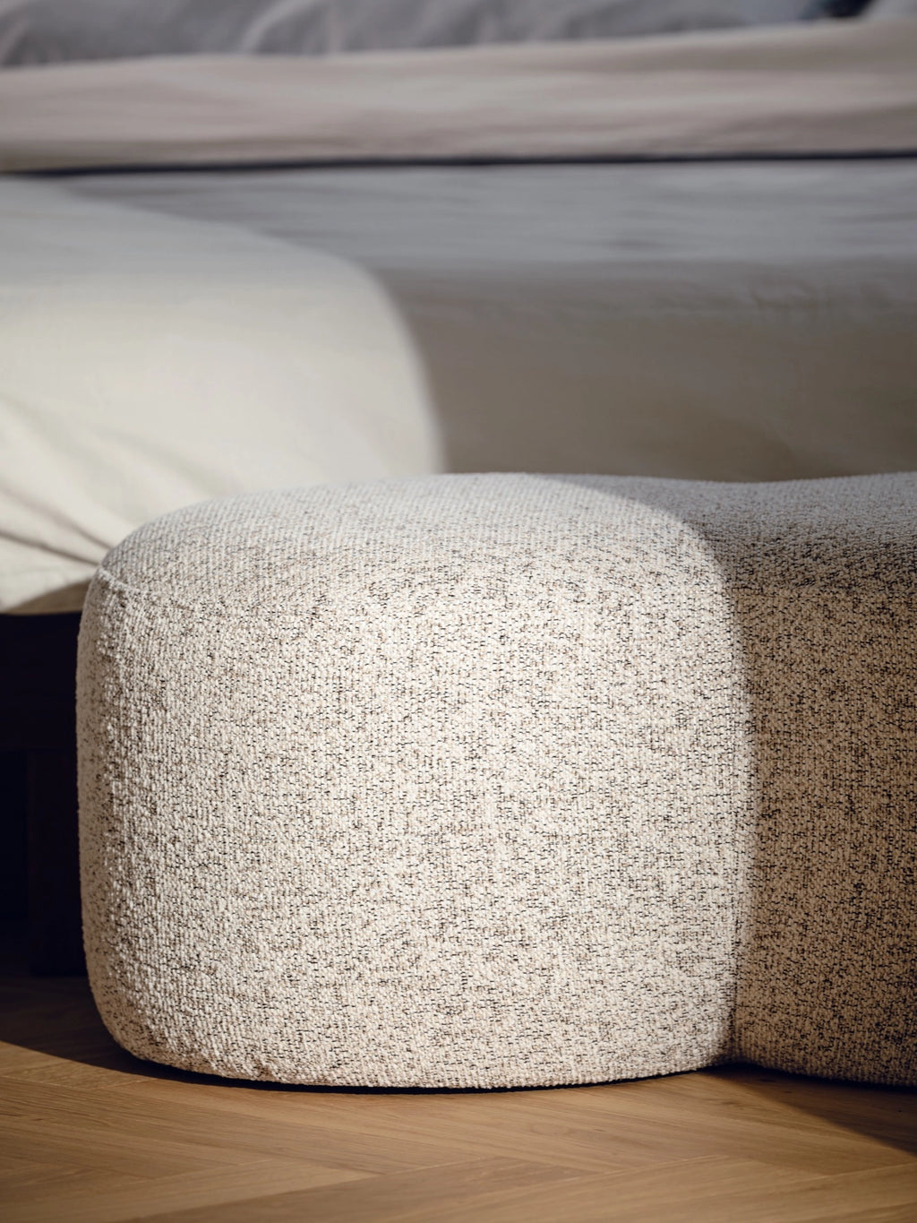 noo.ma Umbo Pouf, an organic modern pouf upholstered in a rich, natural cream bouclé fabric with a textured, speckled weave and soft, rounded silhouette. This contemporary accent piece is perfect as a stylish living room ottoman, a cozy bedroom accent, or minimalist entryway seating.