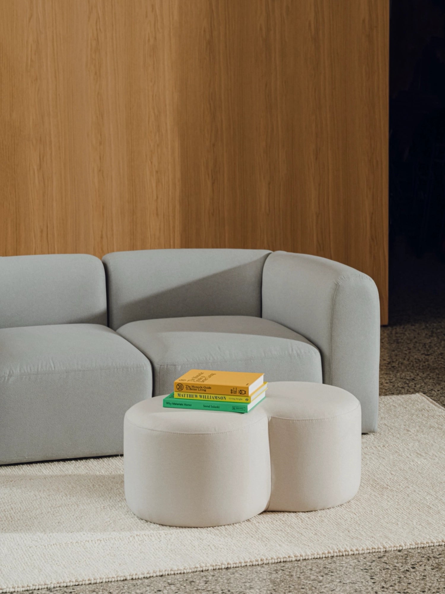 noo.ma Umbo Pouf, a modern minimalist cylindrical pouf upholstered in a soft, light beige fabric with a smooth, rounded profile and clean lines. This versatile contemporary ottoman is perfect as a stylish accent footstool or extra seating for a Scandinavian living room, cozy bedroom, or organic modern lounge area.
