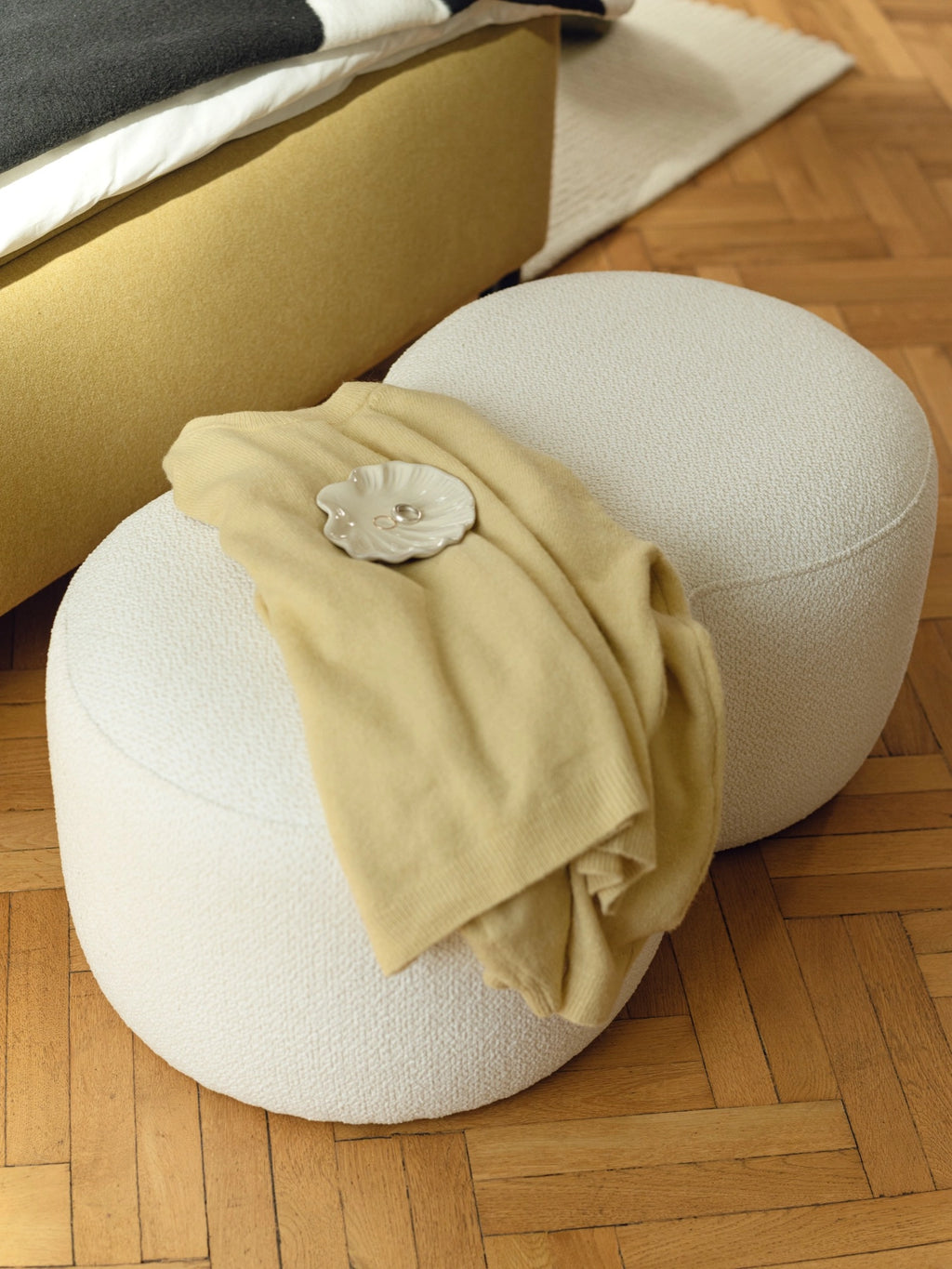 noo.ma Umbo Pouf, a soft, round organic modern pouf upholstered in a textured off-white bouclé fabric, featuring a plush, inviting surface and clean, minimalist lines. This contemporary cream ottoman is perfect as accent seating or a footrest for Scandinavian living rooms, cozy bedrooms, or organic modern interiors.