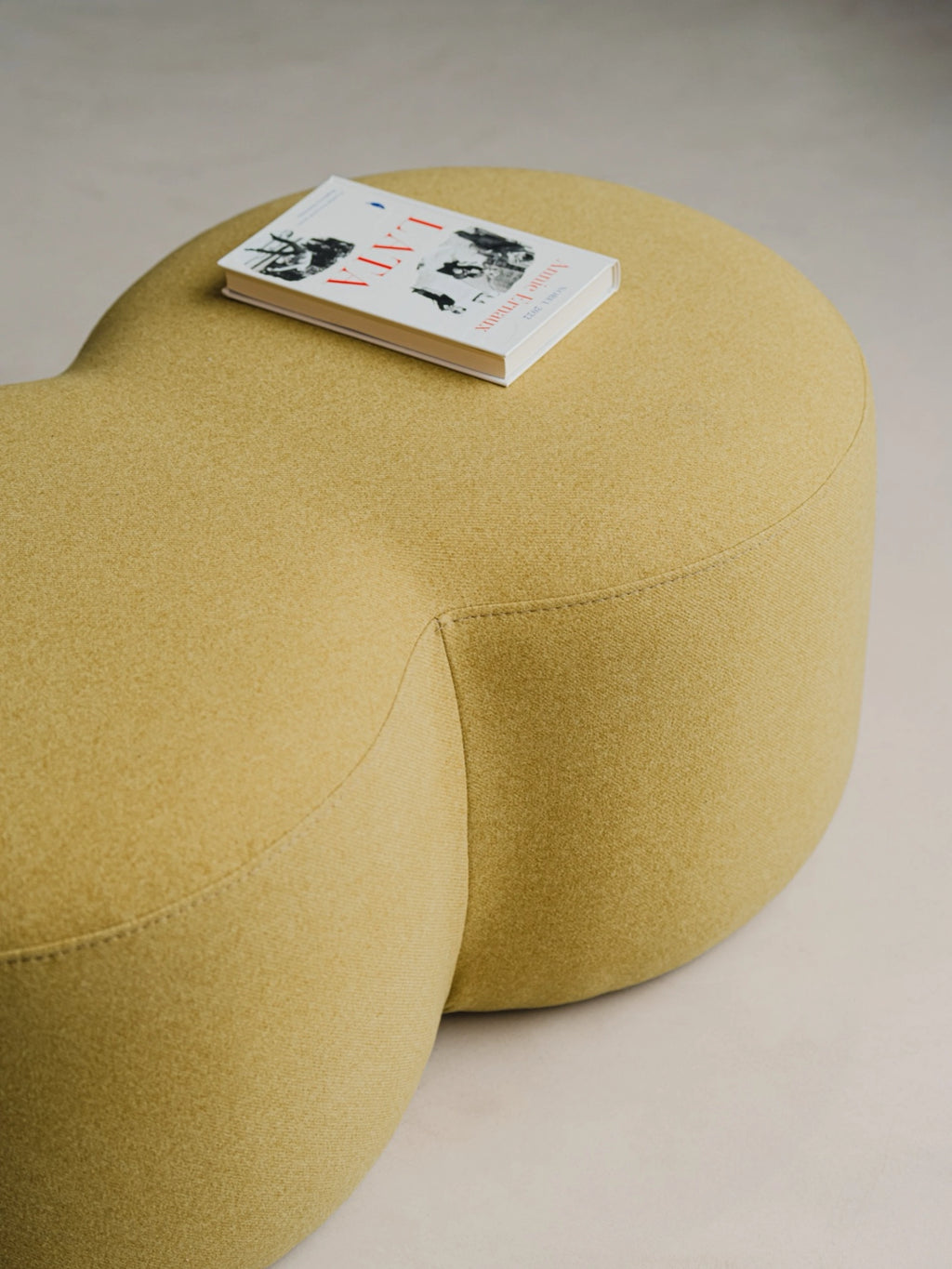 noo.ma Umbo Pouf, a contemporary organic modern pouf upholstered in a textured chartreuse green fabric with a soft, inviting weave and a distinctive biomorphic, rounded shape. This sculptural accent ottoman features clean stitching and a plush, comfortable form, perfect as versatile extra seating or a stylish footrest. Ideal for minimalist living rooms, Scandinavian bedrooms, or cozy reading nooks, adding a pop of warm green color and modern design.