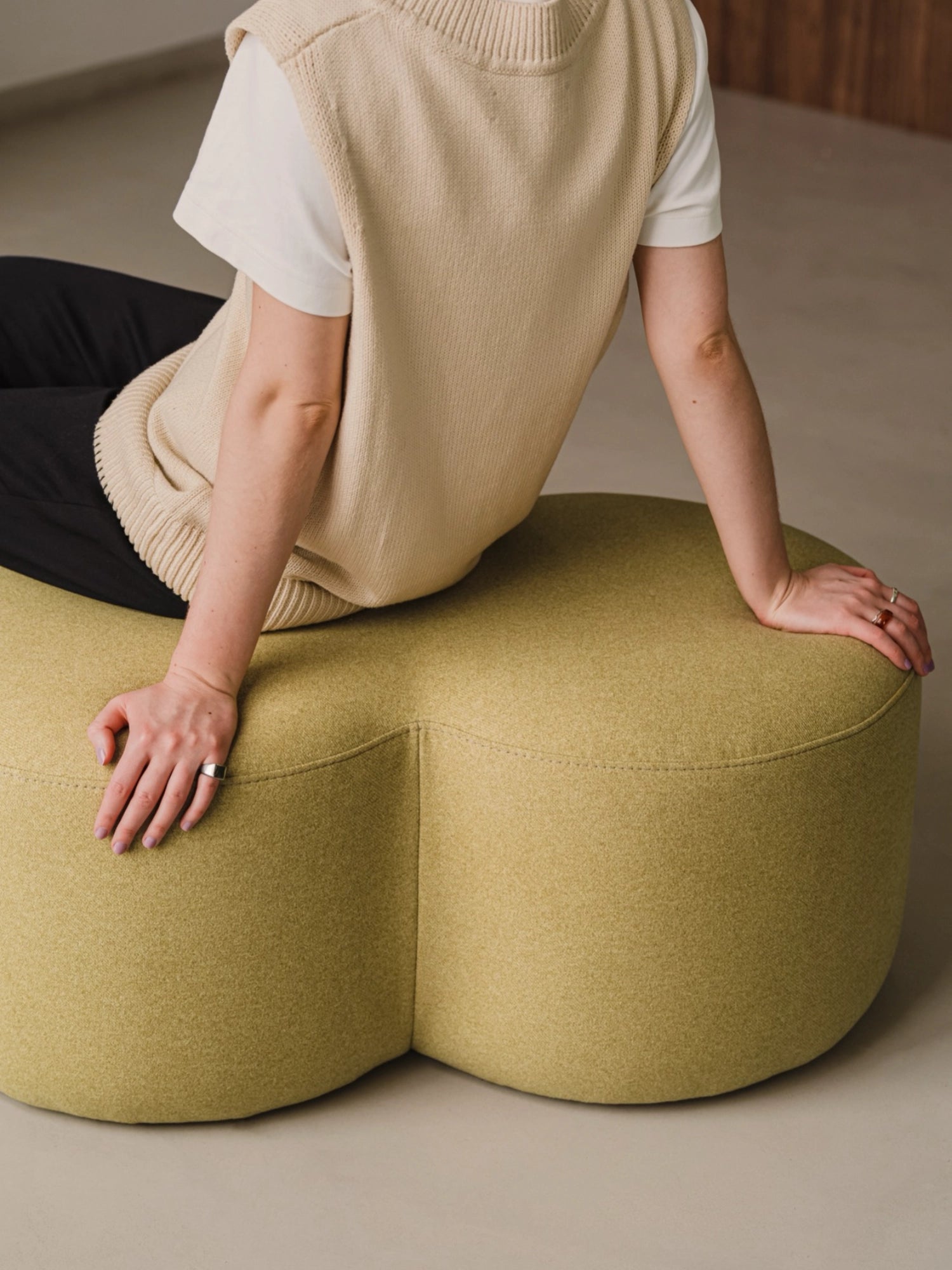 noo.ma Umbo Pouf, an organic modern pouf featuring a unique biomorphic shape with two connected rounded sections, upholstered in a soft, textured pale olive green fabric. This sculptural accent seating piece offers comfortable extra seating or a stylish footrest for contemporary living rooms, minimalist bedrooms, or cozy reading nooks.