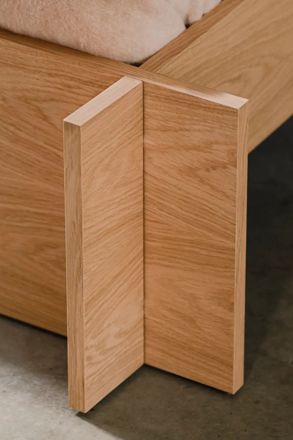 noo.ma Valt Bed, a modern minimalist bed frame crafted from light natural solid oak wood with visible grain and a smooth finish, featuring striking interlocking geometric joints for a clean, contemporary design. This Scandinavian-inspired oak bed is perfect for creating a serene japandi bedroom or organic modern sleeping space.