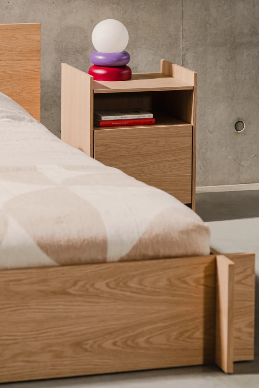noo.ma Valt Bed, a minimalist solid oak bed frame crafted from light natural wood, featuring a clean-lined rectangular silhouette, a simple headboard, and a distinctive footboard with an angled.