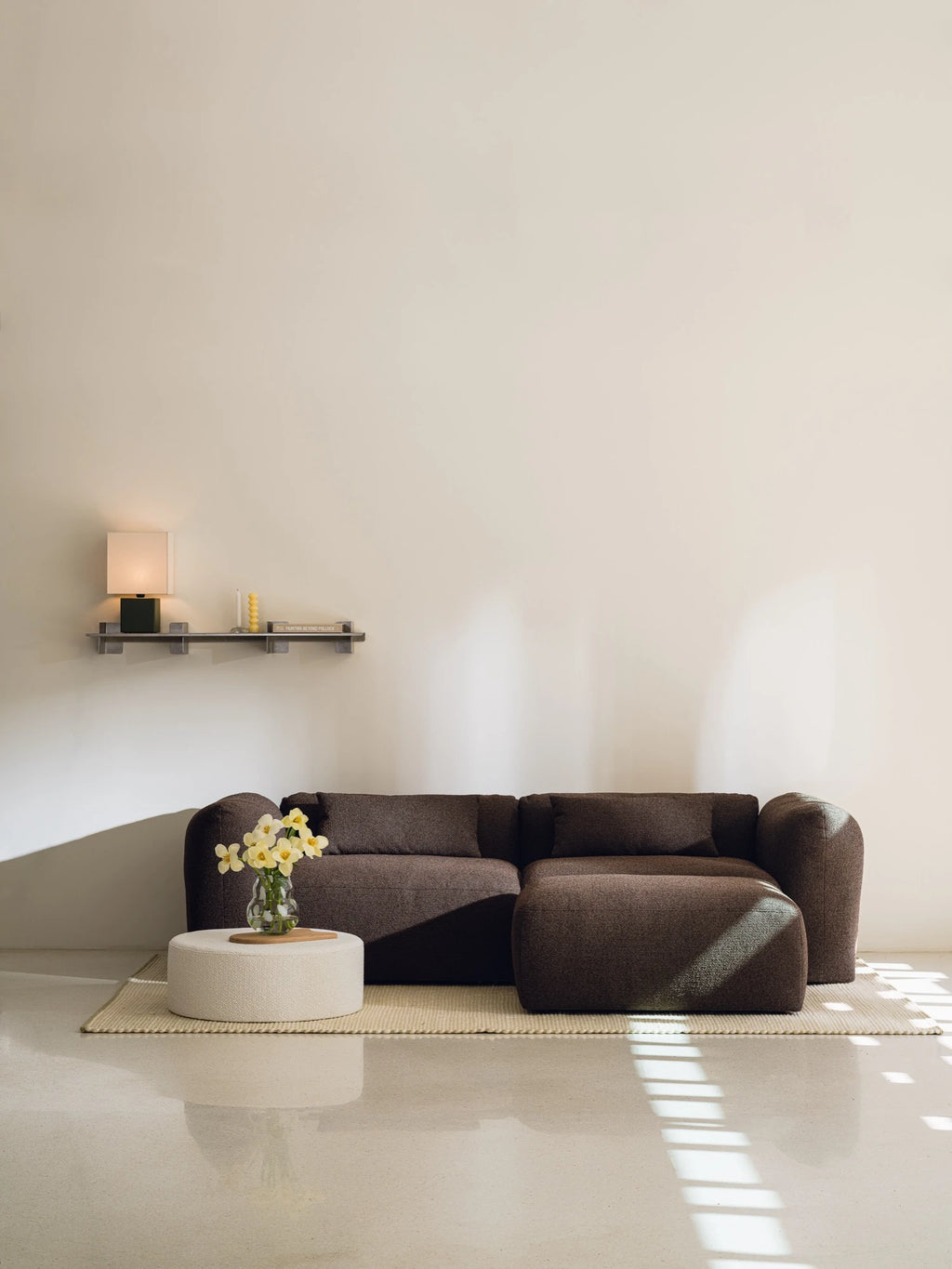 noo.ma Yaro Sofa, a deep chocolate brown modular sofa upholstered in a soft, textured fabric with a plush, inviting feel and a contemporary low-profile design. This organic modern sectional features generously rounded arms, deep seating, and a versatile configuration, making it ideal for comfortable living room lounging or minimalist home decor.