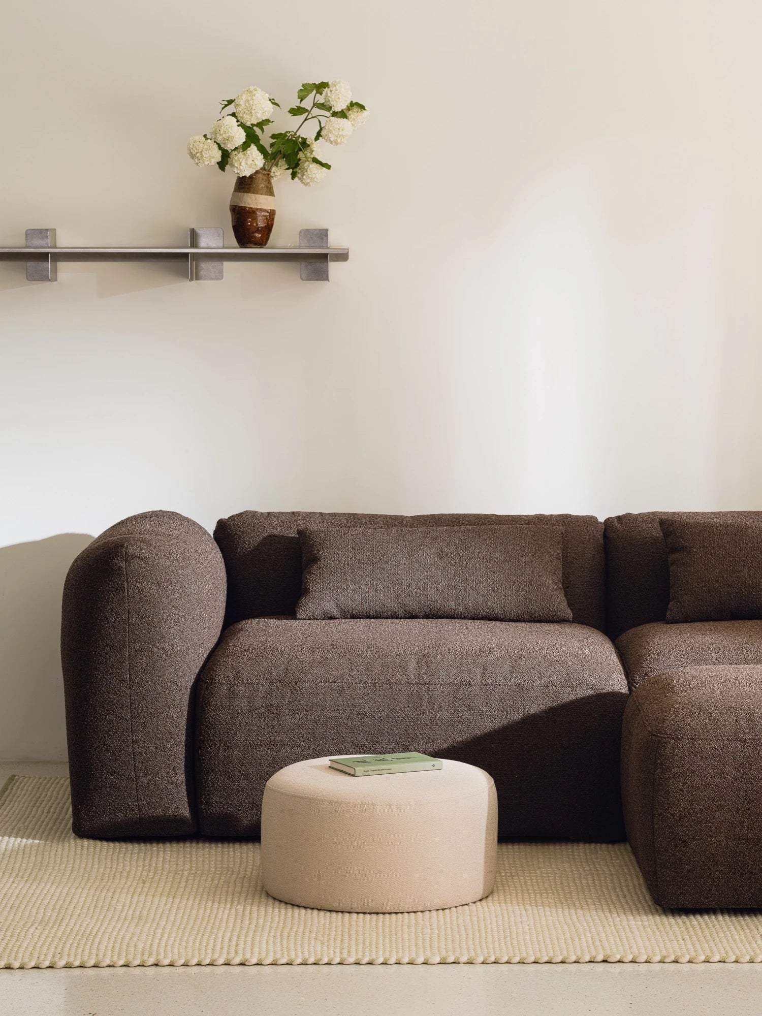 noo.ma Yaro Sofa, a contemporary dark brown modular sofa featuring plush, textured bouclé-style fabric upholstery and soft, rounded organic curves. This cozy living room sofa offers deep seating and a minimalist silhouette, designed for ultimate comfort. Ideal for modern minimalist or organic modern interiors seeking comfort and style.