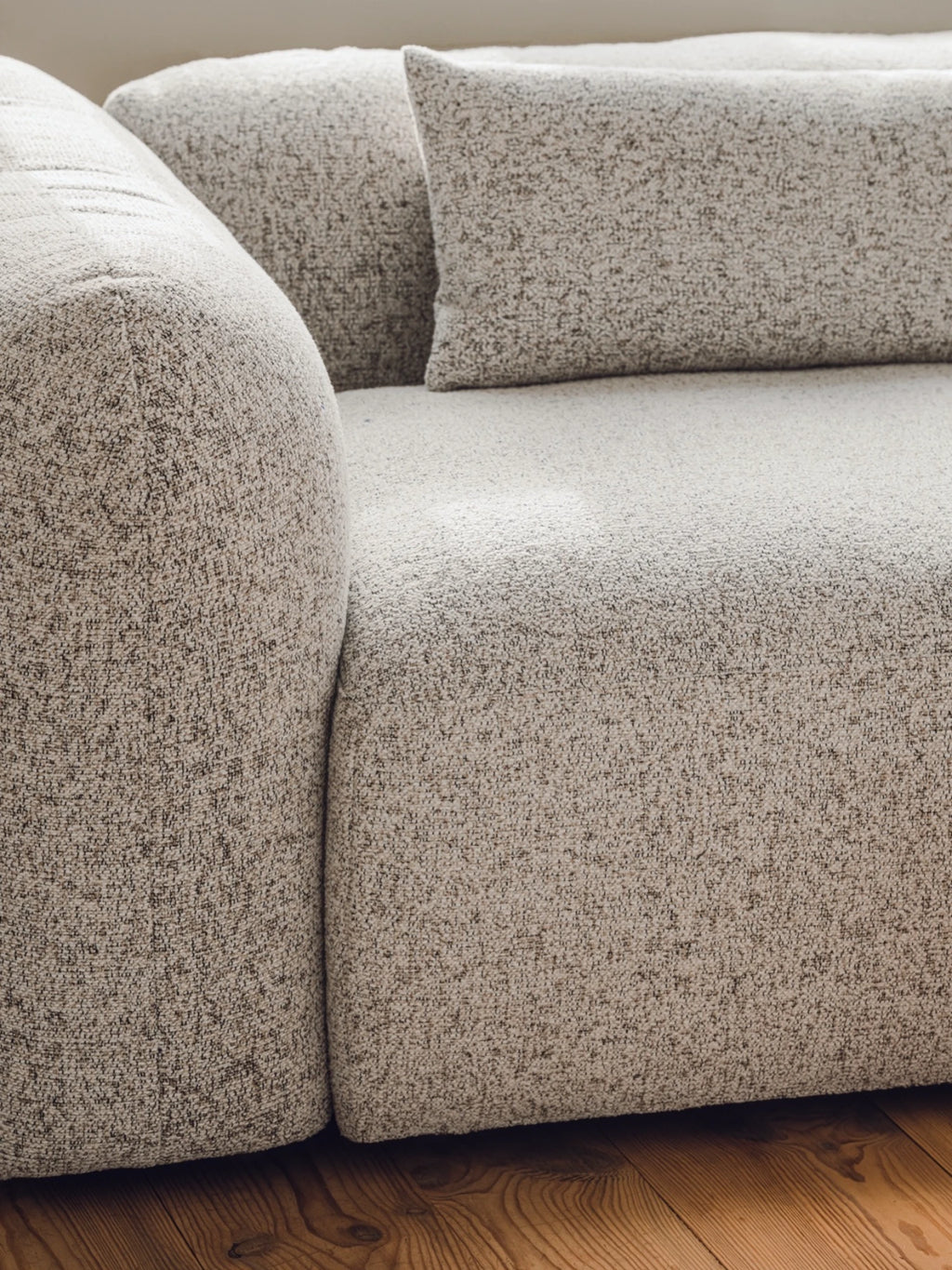 noo.ma Yaro Sofa, a contemporary organic modern sofa featuring a plush, inviting silhouette with soft rounded arms and deep seating. Upholstered in a richly textured, speckled beige bouclé fabric with natural brown and cream tones, offering a cozy yet refined aesthetic. Ideal for creating a warm, minimalist living room or a comfortable Scandinavian lounge space.