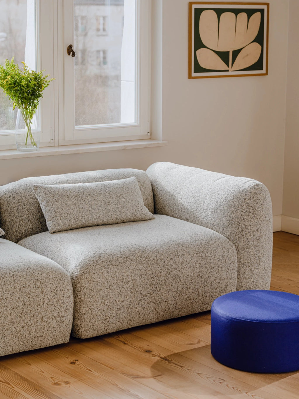 noo.ma Yaro Sofa, a modular organic modern sofa upholstered in a light grey textured bouclé fabric with a speckled, oatmeal-like finish. It features a rounded, plump silhouette, deep seating, and a matching rectangular lumbar pillow, offering a cozy and inviting aesthetic. This versatile contemporary sectional is perfect for minimalist living rooms, Scandinavian interiors, or creating a comfortable modern lounge area.