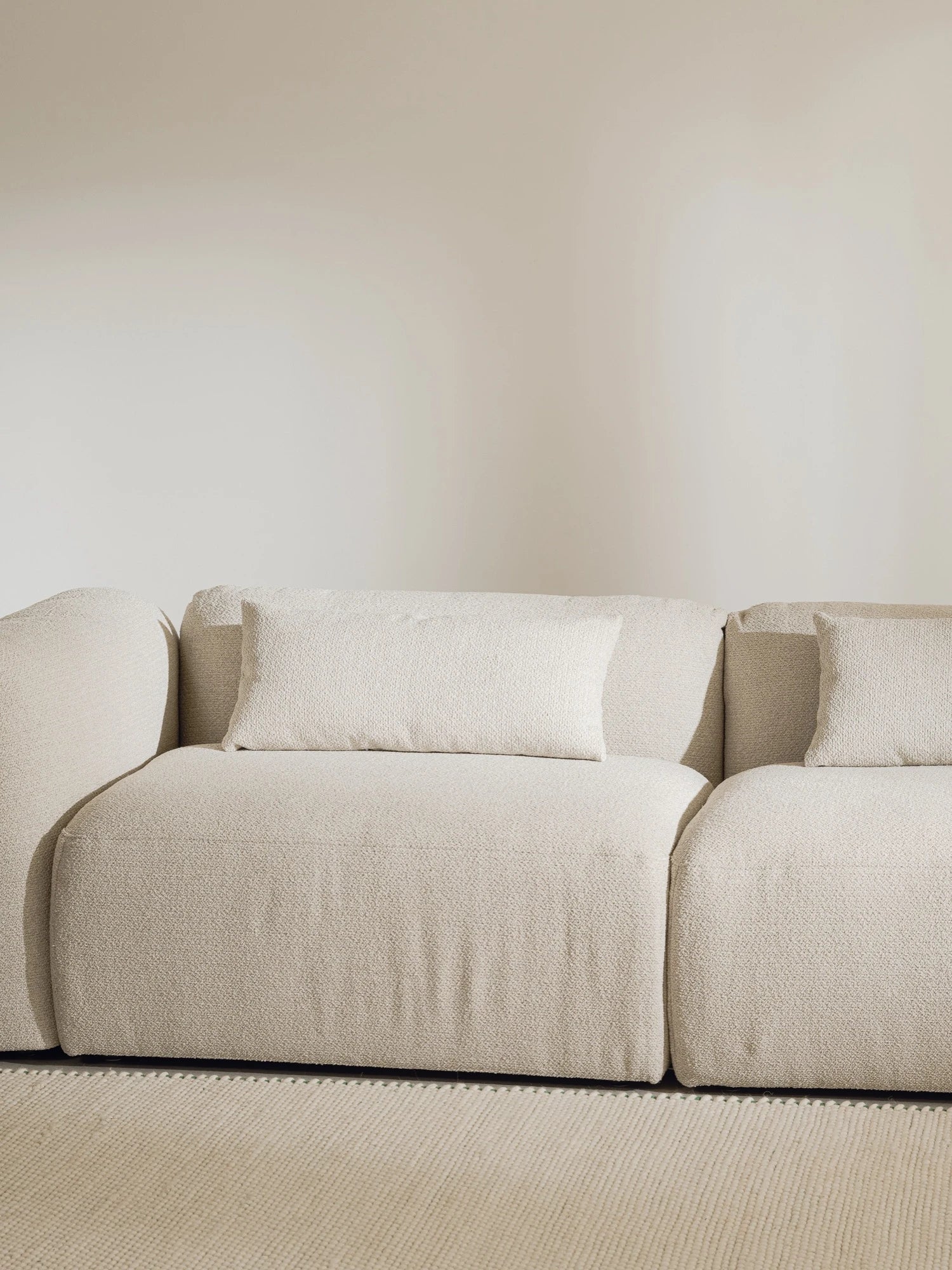 noo.ma Yaro Sofa, a contemporary modular sofa upholstered in a soft cream textured bouclé fabric with a low-profile silhouette and deep, inviting seats. Its organic modern design features rounded arms and plush back cushions, offering comfort and minimalist elegance. Perfect as a Japandi or Scandinavian living room sofa for stylish, relaxed interiors.
