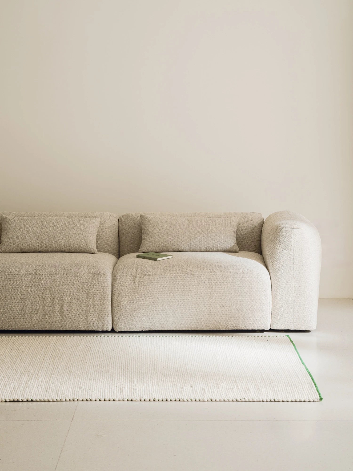 noo.ma Yaro Sofa, a contemporary modular sofa upholstered in a light beige textured bouclé fabric, featuring a low-profile design, gently rounded arms, and deep seating. This minimalist cream sofa is an ideal choice for organic modern living rooms or Scandinavian-inspired spaces.