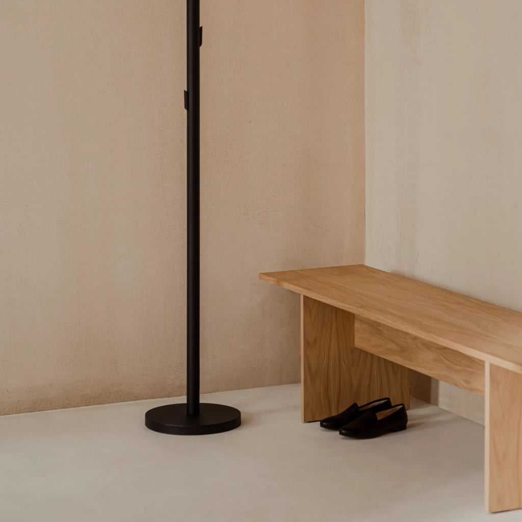 noo.ma Yuko Coat Rack, a sleek modern minimalist coat stand crafted from durable matte black metal with a slender vertical pole, a sturdy round base, and multiple discreet pegs for hanging. This contemporary hall tree provides stylish and functional storage, perfect for an entryway, hallway, or bedroom in a Scandinavian or industrial chic interior.