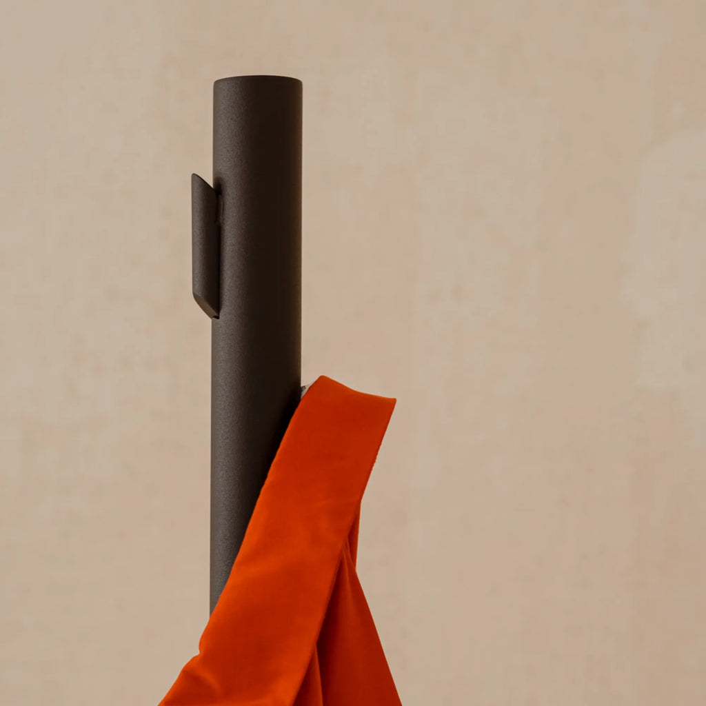 noo.ma Yuko Coat Rack, a sleek modern minimalist standing coat rack crafted from dark matte powder-coated steel with a tall cylindrical profile and an integrated, subtly curved hook. This contemporary metal coat rack provides elegant entryway organization and stylish hallway storage for modern Scandinavian and minimalist interiors.