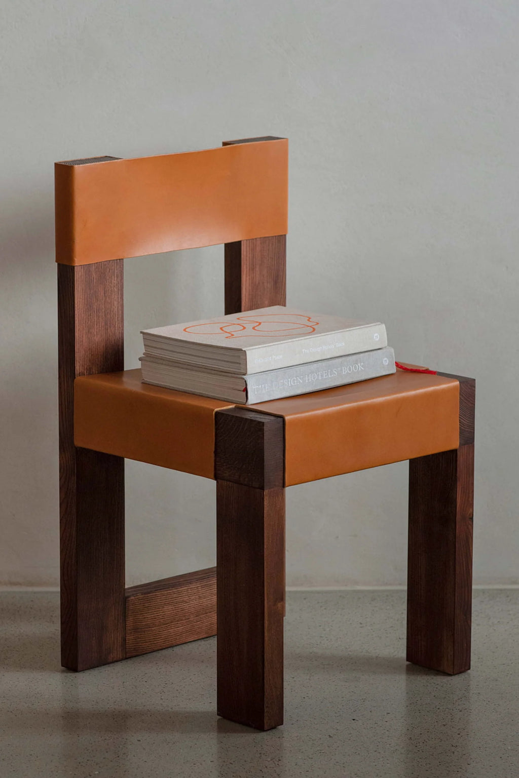 NG DESIGN Object 118 Chair, a luxury mid-century style chair featuring a dark stained wooden frame and tan leather seat and back, photographed in a studio. The perfect authentic leather accent piece for any modern interior.