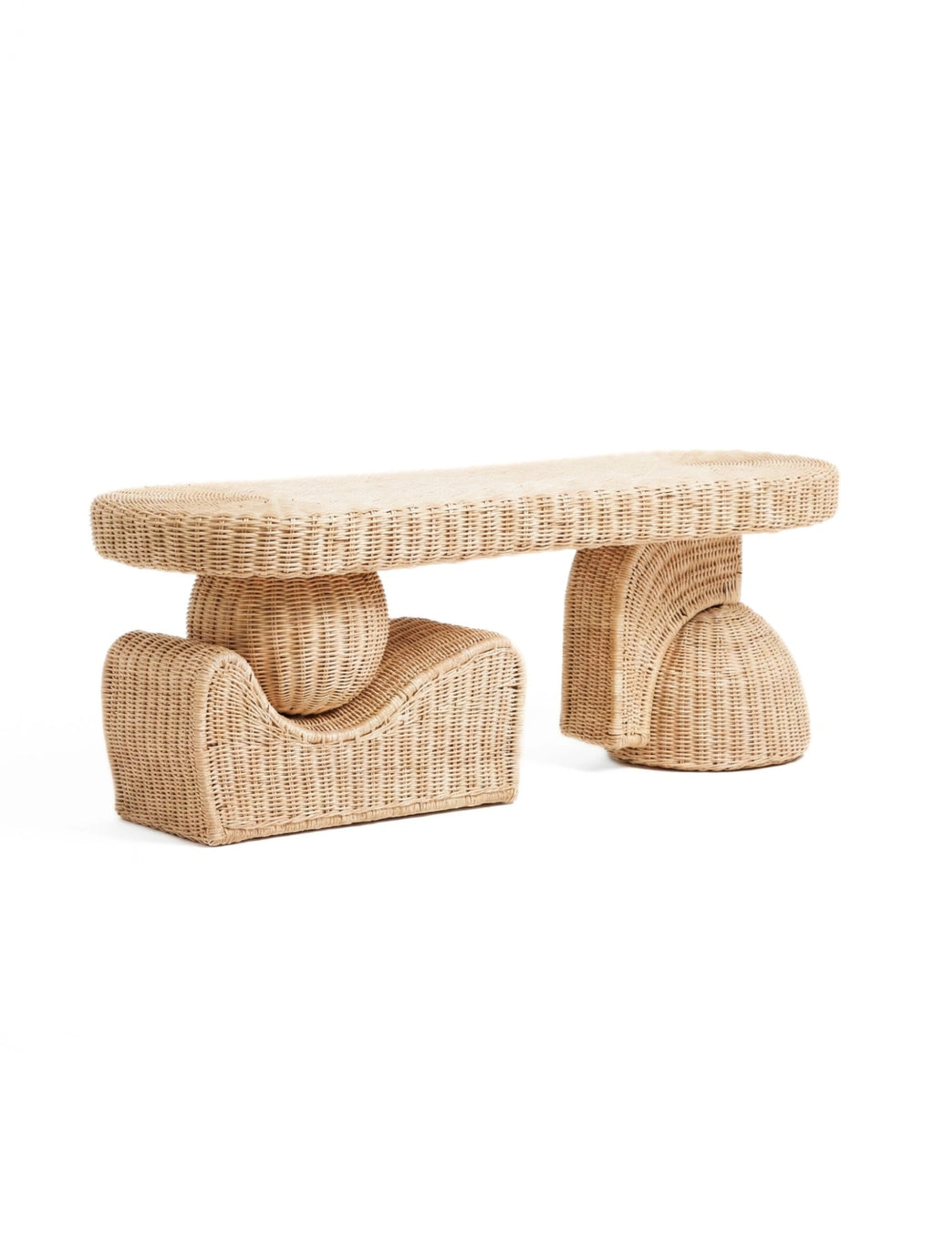 Heaps & Woods Alfred Bench, a natural light rattan bench featuring a distinctive sculptural, organic modern design with an elongated oval woven top. Its unique base combines a rounded spherical support on one side with a curved, flowing shape on the other, all crafted from finely woven rattan in a warm, light beige tone. This contemporary rattan bench is perfect as an entryway console, living room accent piece, or stylish bedroom bench for boho and organic modern interiors.