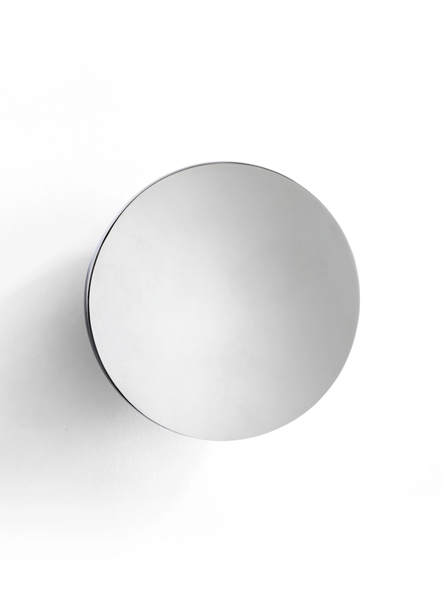 New Works Aura Wall Mirror, a premium circular silver mirror with a sleek, rounded black frame, mounted on a clean white wall. Ideal for contemporary interior design.