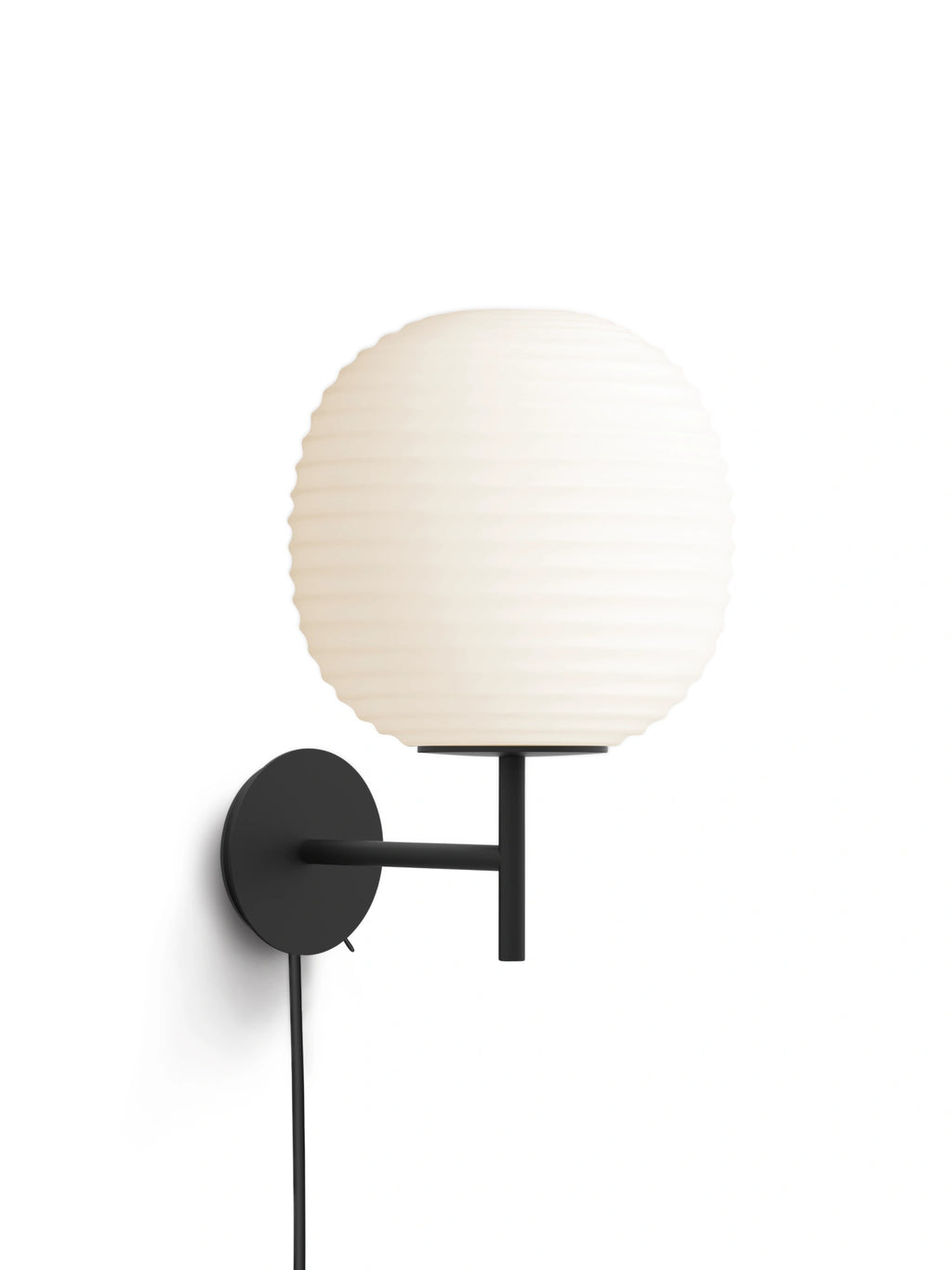 New Works Lantern Wall Lamp: A sleek black metal wall mount with an extending arm holds a premium, round, cream-colored ribbed opal glass shade. Creates ambient lighting.