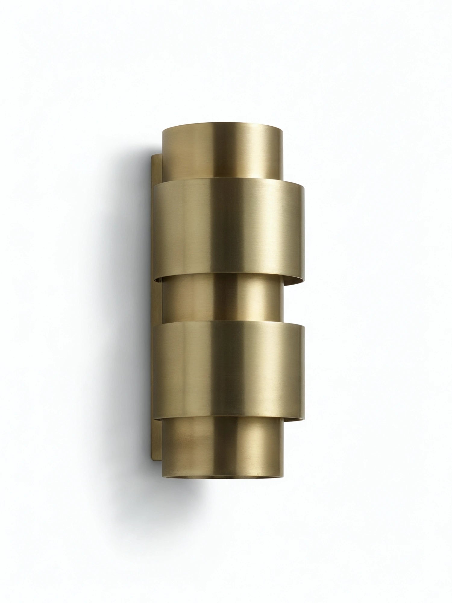 CTO Lighting Ring Wall Lamp - Short, a sophisticated wall-mounted light fixture crafted from stacked, concentric brass rings, creating a layered, sculptural effect with a warm metallic finish, against a white wall.