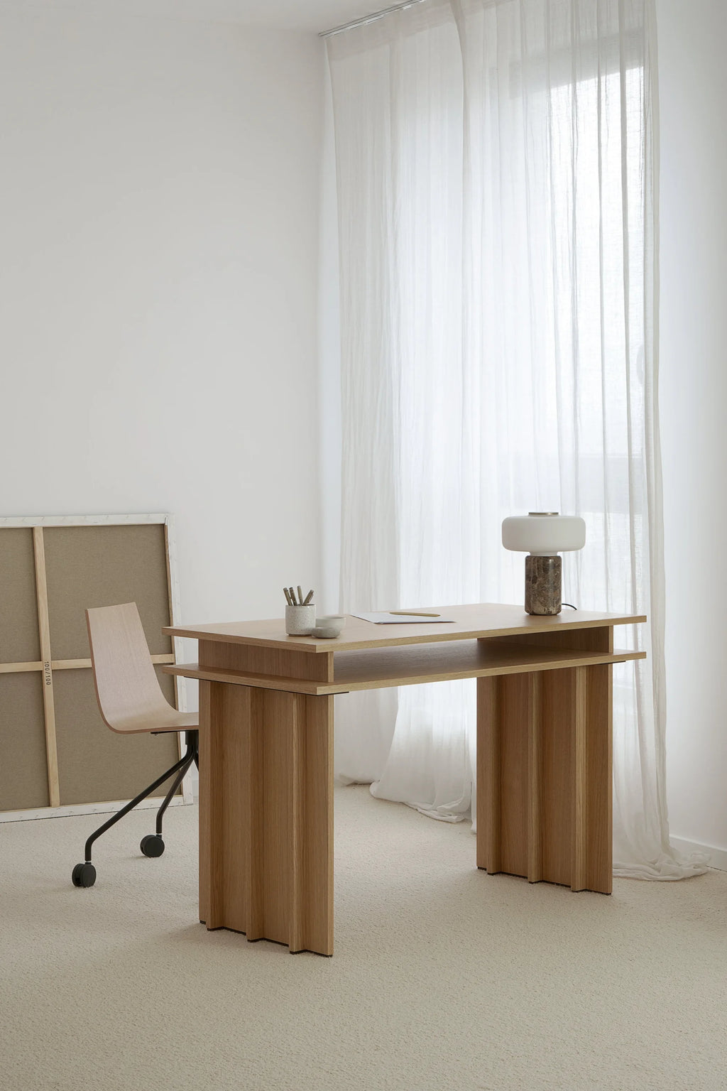 TAMO Piato Desk in a lifestyle setting, showcasing its light oak with subtle wood grain, featuring a floating tabletop, and ribbed, sculptural legs. This premium wooden desk is perfect for a modern office.