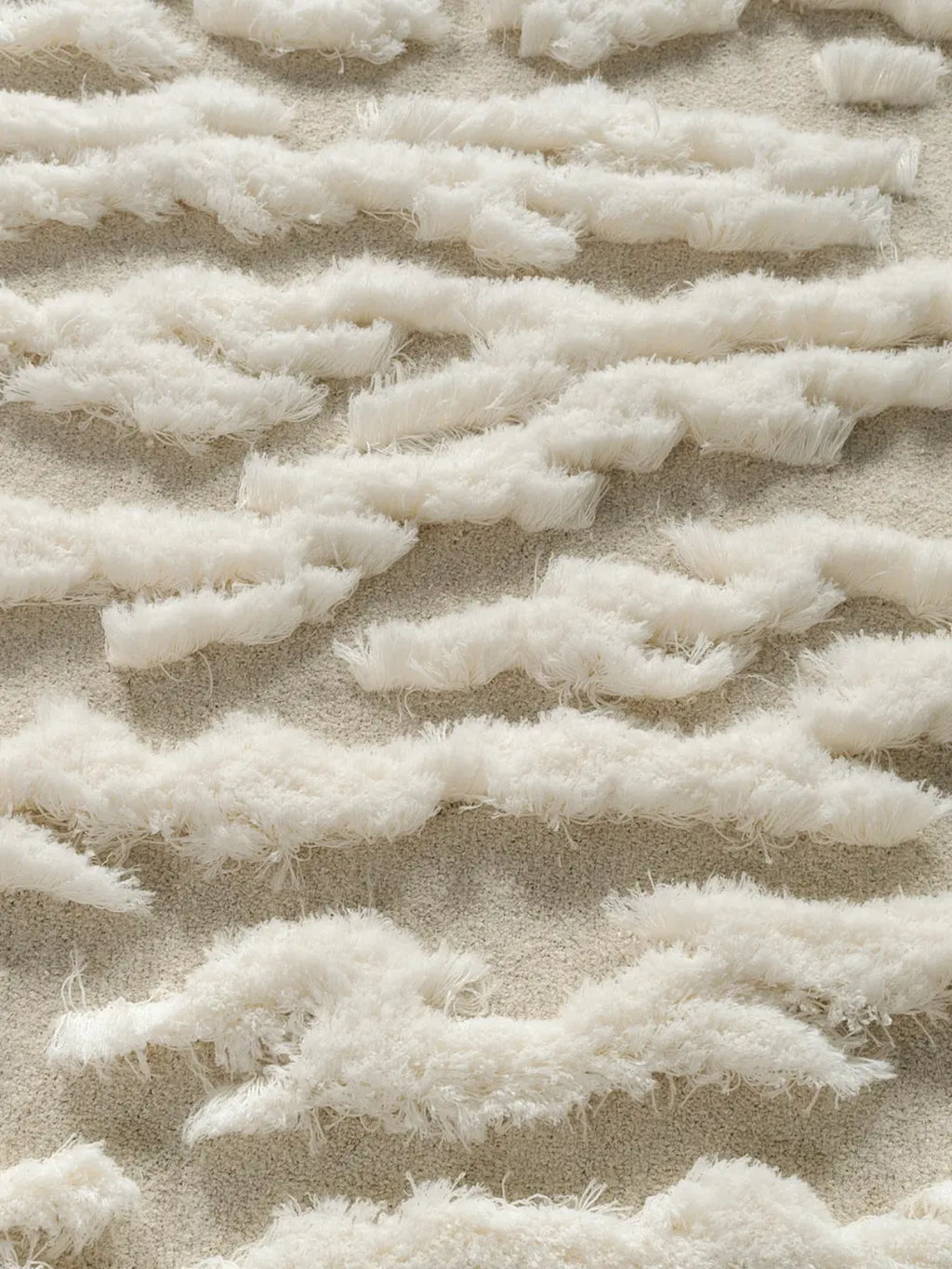 alp_ Plage Sauvage Rug, a cream-colored textured area rug featuring a distinctive high-pile shaggy wave pattern in natural off-white over a finely woven low-pile beige base.