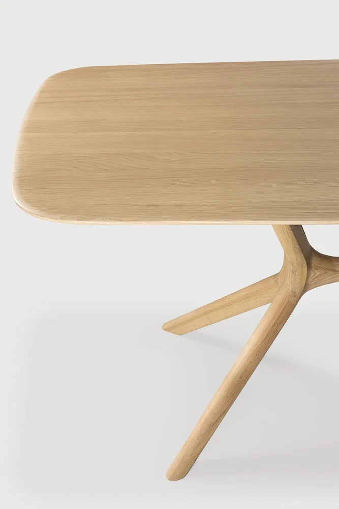 Ethnicraft X Dining Table, a modern minimalist dining table crafted from solid natural light oak wood, featuring a smooth rectangular tabletop with gently rounded corners. Its distinctive sculptural X-shaped base, also in light oak, creates an organic, contemporary aesthetic. This Scandinavian-inspired wood dining table is perfect for modern dining rooms or open-plan living spaces.
