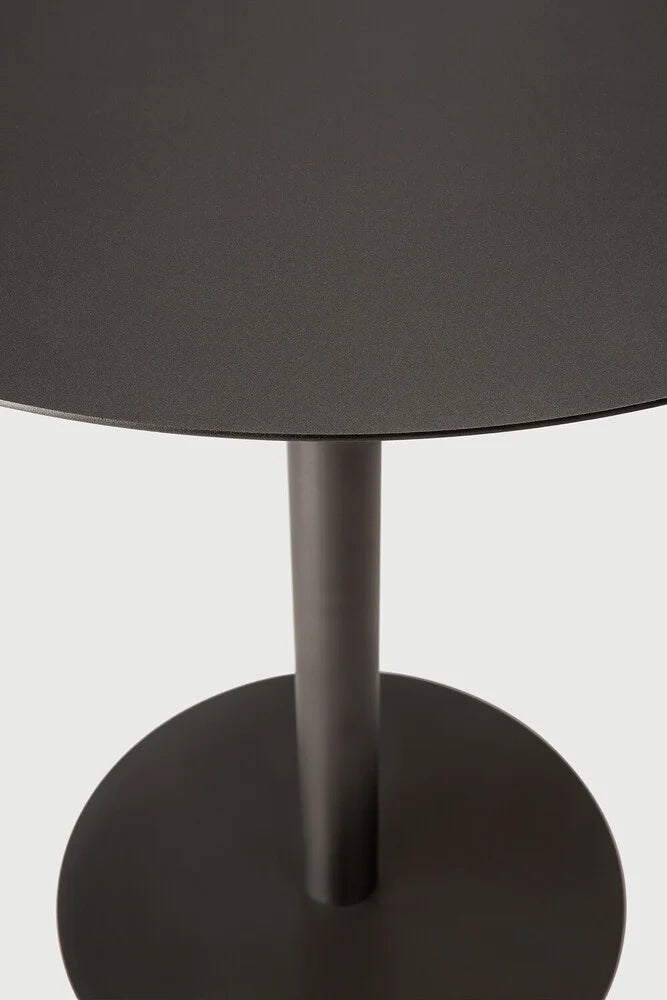 Ethnicraft Blend Round Dining Table, a sleek modern minimalist dining table crafted from matte black metal with a finely textured finish. It features a clean round tabletop supported by a sturdy cylindrical pedestal base, embodying a contemporary industrial chic aesthetic. Perfect for small dining rooms, modern kitchens, or as a stylish bistro table.