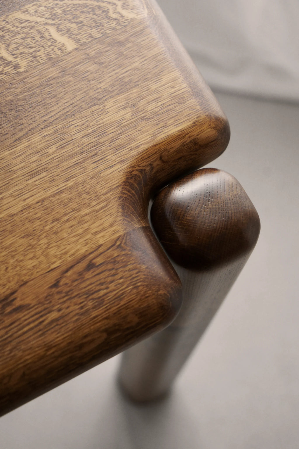 TAMO Puffo Desk, close-up of premium dark stained oak wood with visible grain texture, smooth rounded edges, and unique joint design. Ideal for modern home office.
